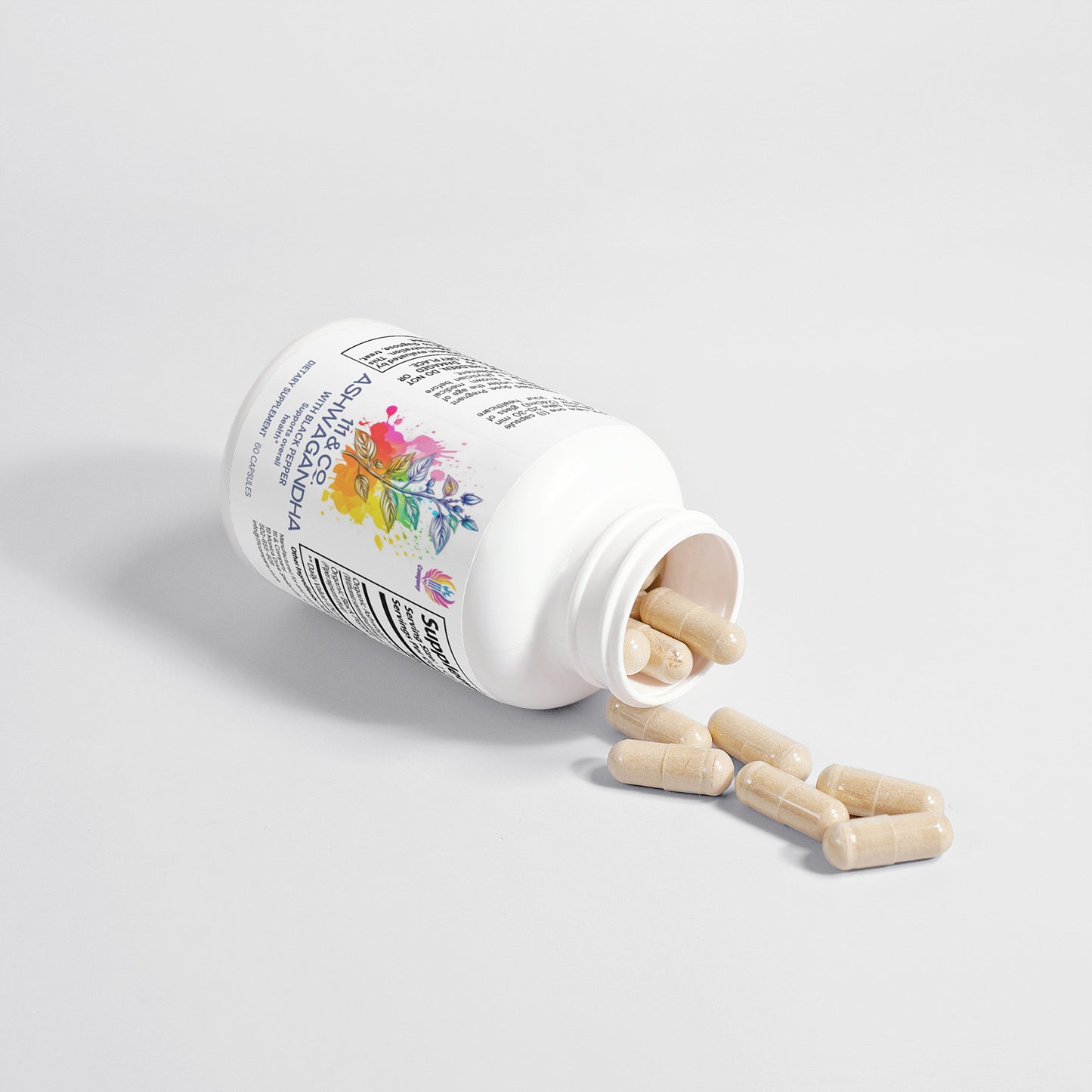 A white bottle of dietary supplements labeled 111 & Company Ashwagandha (with Black Pepper) rests on a light gray background, hinting at adaptogenic power. The label has colorful floral designs, with beige capsules spilling onto the surface from the open bottle.