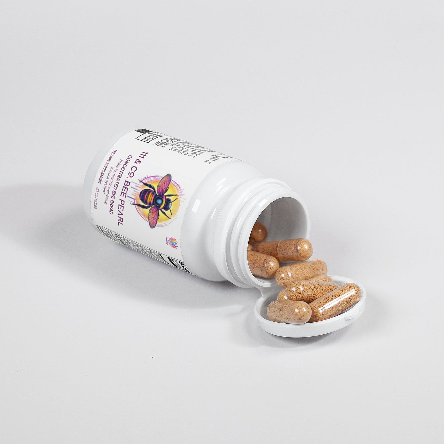 A partially opened white bottle of 111 & COMPANY BEE PEARL capsules from 111 & Company spills several brown capsules onto the surface, with a colorful bee illustration adding a whimsical touch to the plain background.