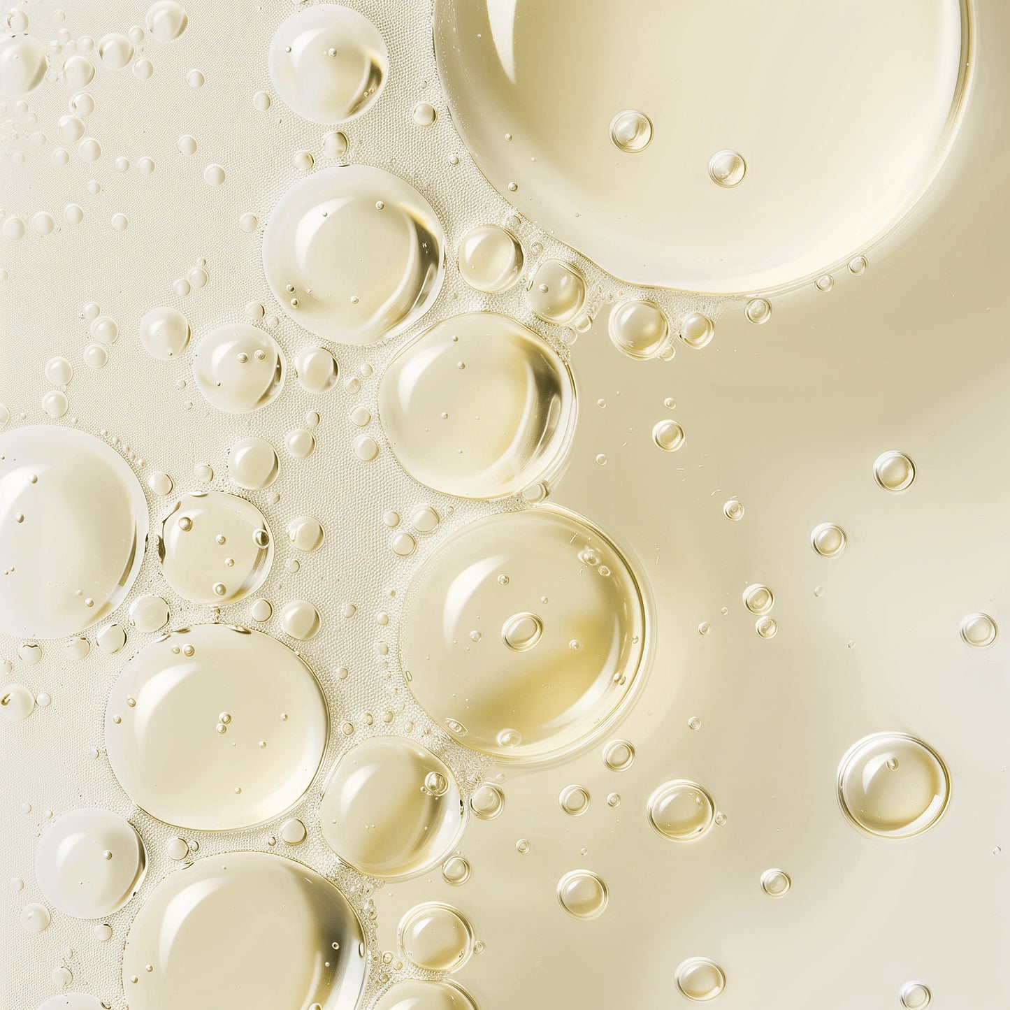 A close-up of transparent oil droplets, infused with botanical ingredients from 111 & COMPANY BOTANICAL HAIR GROWTH SERUM by 111 & Company, float in pale yellow liquid. The spherical shapes create an abstract pattern, reflecting light and evoking depth and fluidity reminiscent of the serum itself.