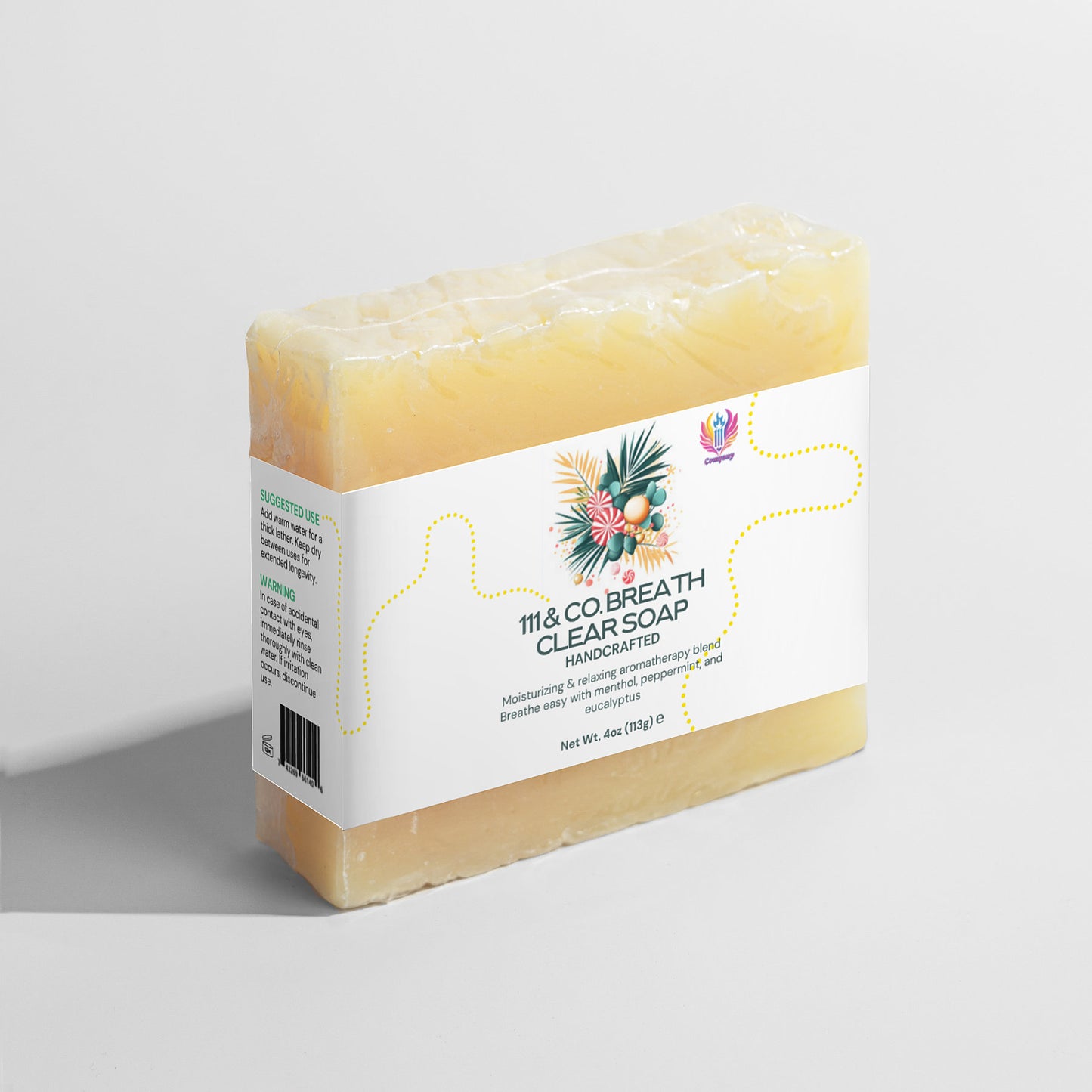 A rectangular, pastel yellow soap bar with a white label stands against a plain background. The label showcases floral graphics with 111 & COMPANY BREATHE CLEAR SOAP and Handcrafted, emphasizing moisturizing benefits and 6oz weight. The soaps texture is smooth with slightly uneven edges.