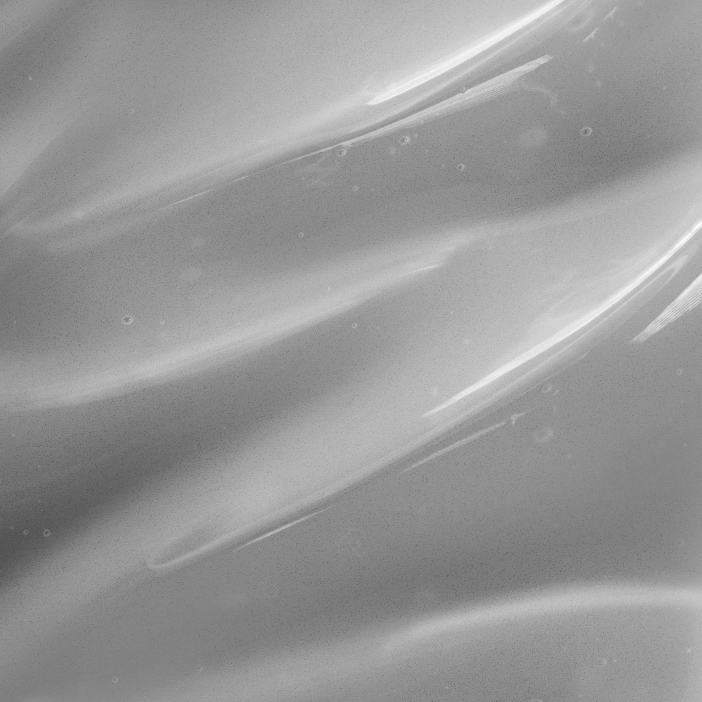 A close-up abstract of smooth, undulating gray and white patterns evokes the essence of the 111 & COMPANY CHARCOAL FACIAL CLEANSER. Its glossy surface mirrors natural ingredients, while tiny bubbles dispersed throughout enhance its dynamic appearance.