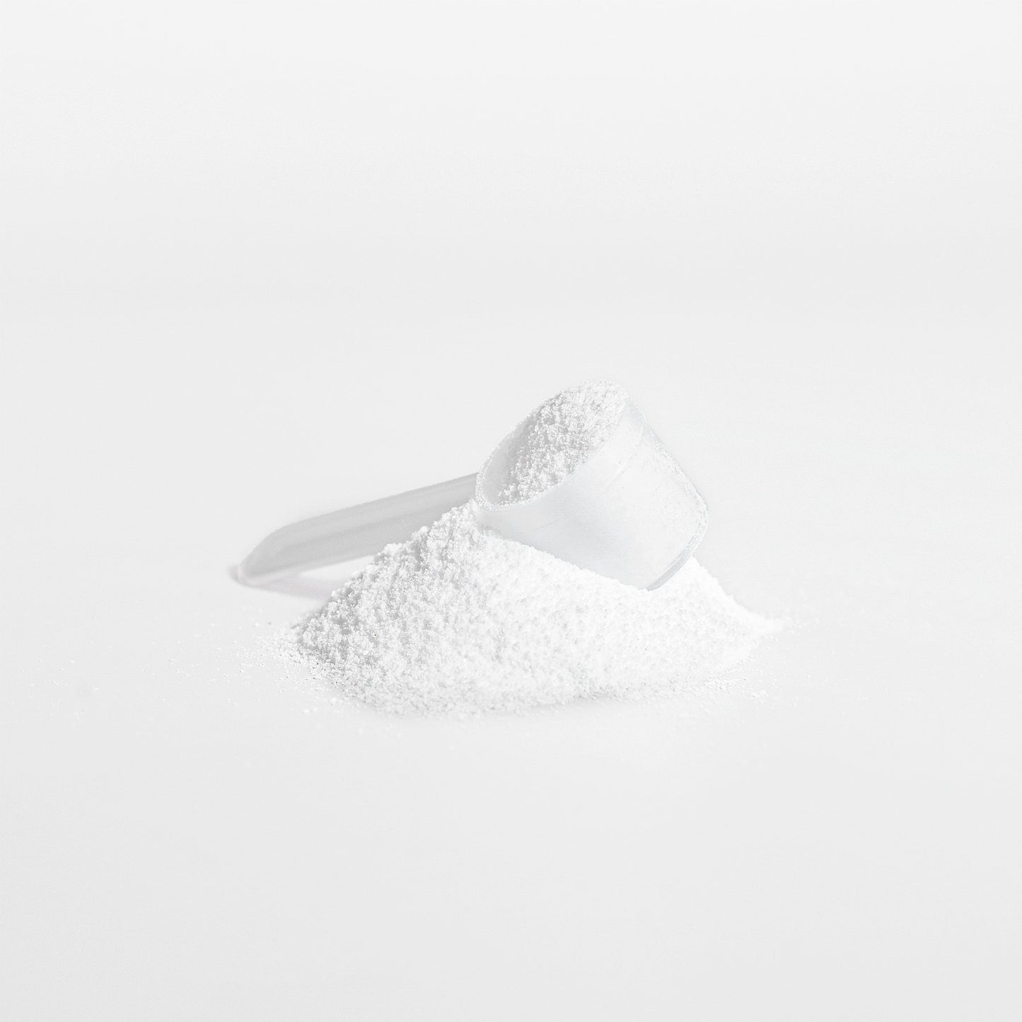 A small transparent scoop filled with fine 111 & Company MaxStrength Creatine Monohydrate rests on a pile of the same powder against a white background. The scoops smooth shine enhances the clean composition, suggesting its role in muscle protein synthesis.