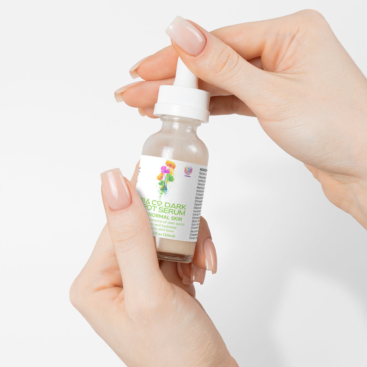 A manicured hand with light pink polish holds a bottle of 111 & Company Dark Spot Serum for Normal Skin. The label, adorned with colorful floral designs, promises dark spot reduction for an even skin tone against a plain white background.