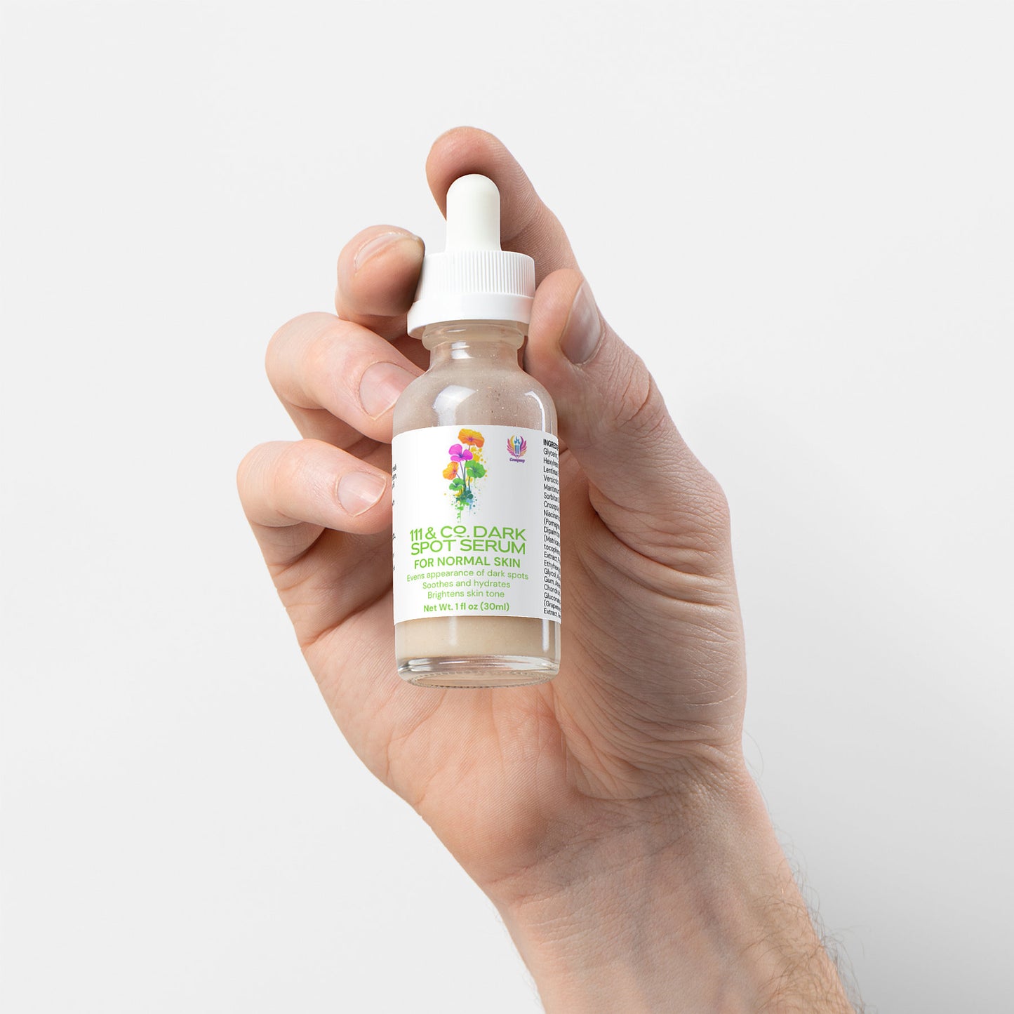 A hand holds a glass dropper bottle labeled 111 & COMPANY DARK SPOT SERUM FOR NORMAL SKIN. Designed for dark spot reduction and even skin tone, the transparent bottle has a white cap. The label, adorned with colorful flowers and detailed product info, stands against a plain white background.
