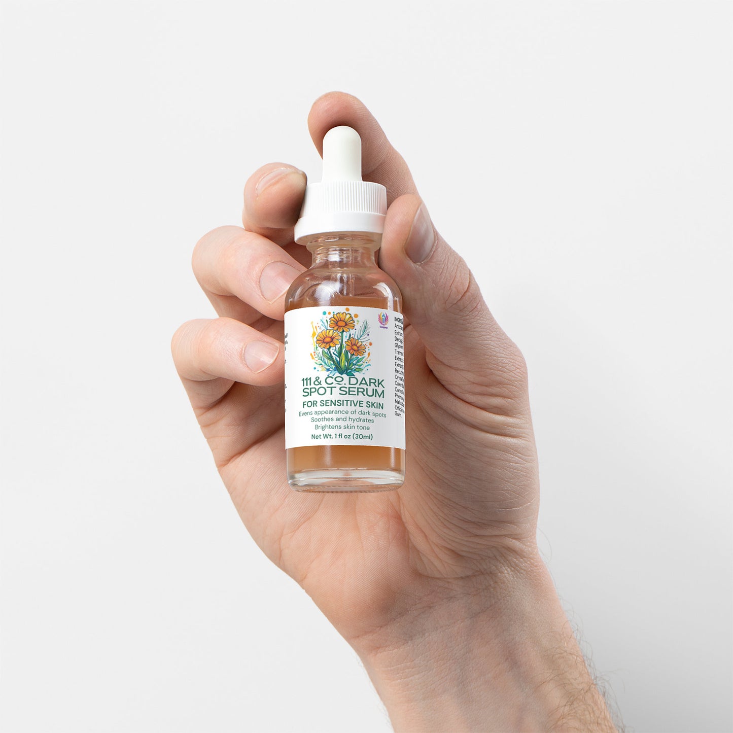 A hand holds a clear 111 & Company Dark Spot Serum bottle with a dropper cap, featuring floral artwork on the label. It highlights a gentle formula for sensitive skin made from natural ingredients. The bottle contains 1 fl oz (30 ml) and is set against a plain white background.