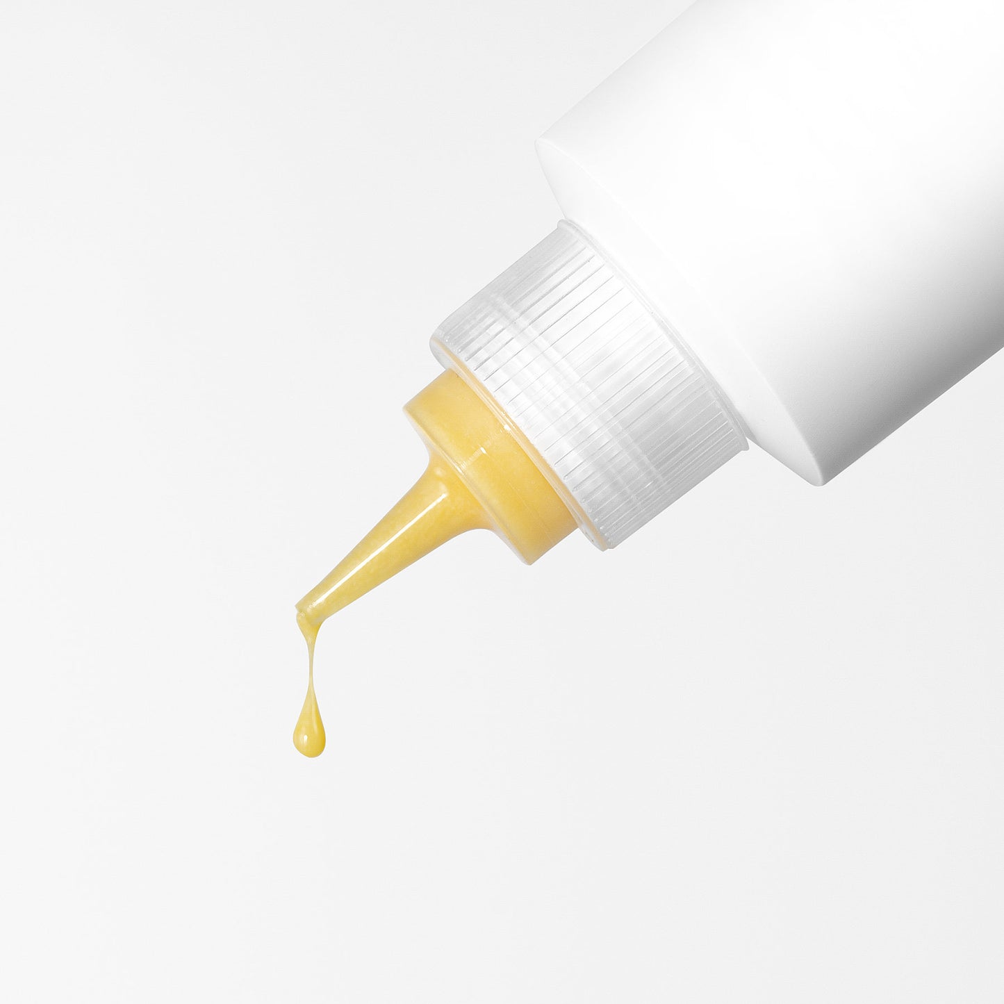 The 111 & COMPANY DOG SKIN SOOTHING CREAM dispenses a golden antioxidant-rich droplet infused with ceramides from a white squeeze bottle. The textured, translucent cap adds elegance against the plain white background as the liquid is poised to fall.