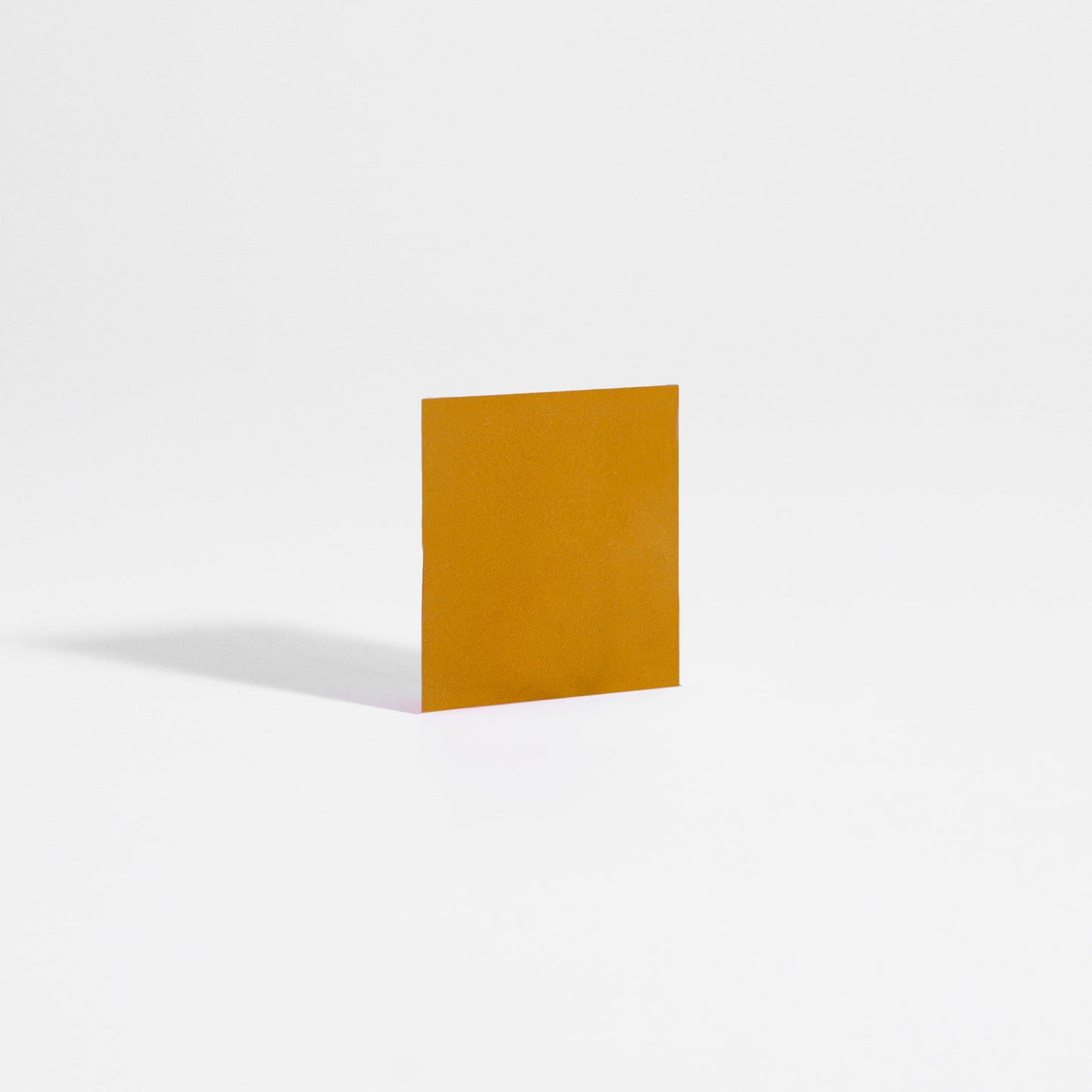A square of mango and orange Hangover Strips from 111 & Company stands upright on a smooth white surface, casting a faint shadow to its left. Reminiscent of Ayurvedic practices, the strips vivid packaging is highlighted against the clean, minimalist background.