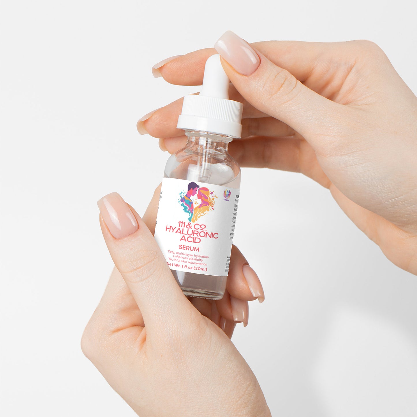Close-up of hands holding a small transparent bottle labeled 111 & COMPANY Hyaluronic Acid Serum for hydration and skin rejuvenation, featuring a white dropper cap on a plain white background. The persons manicured, natural nails add elegance to the scene.