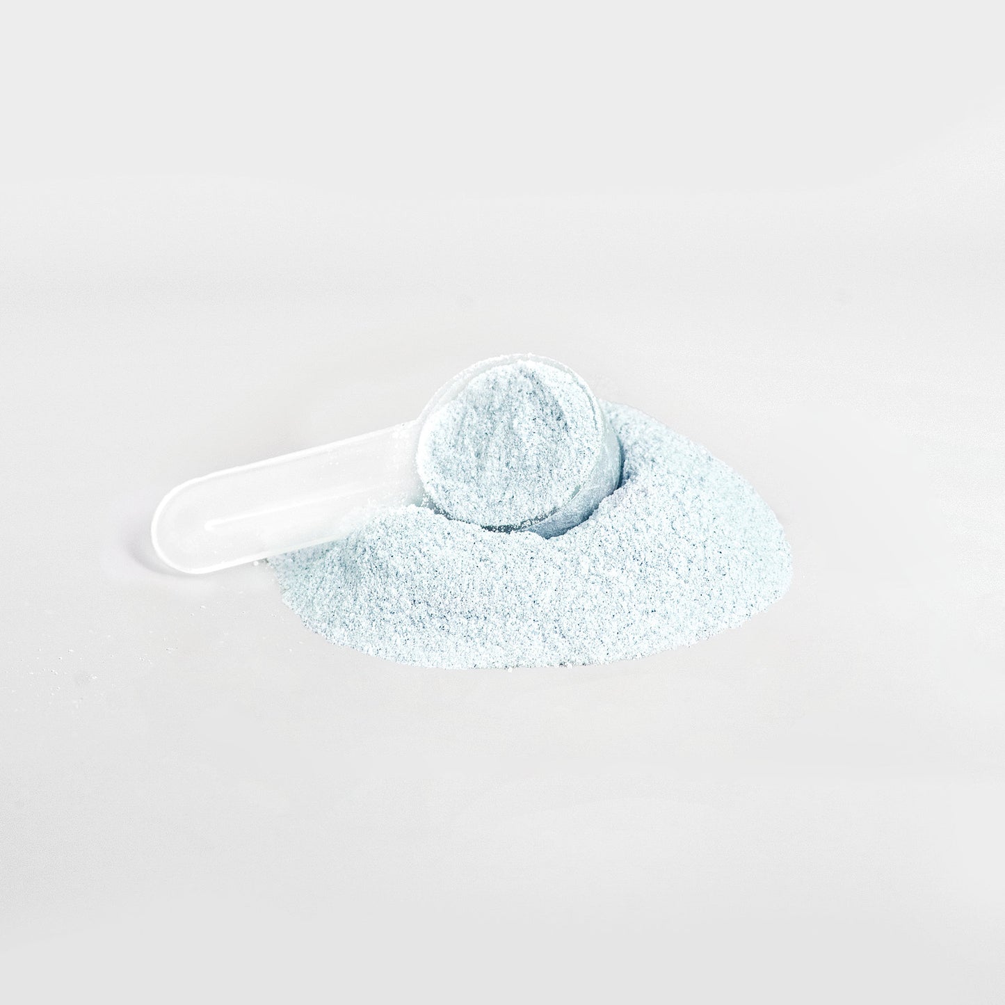 A white plastic scoop is partially buried in a small pile of 111 & Company Hydration Powder (Matcha Green Tea) against a plain white background. The finely textured, electrolyte-rich powder is scattered loosely, suggesting precise measuring or dispensing.