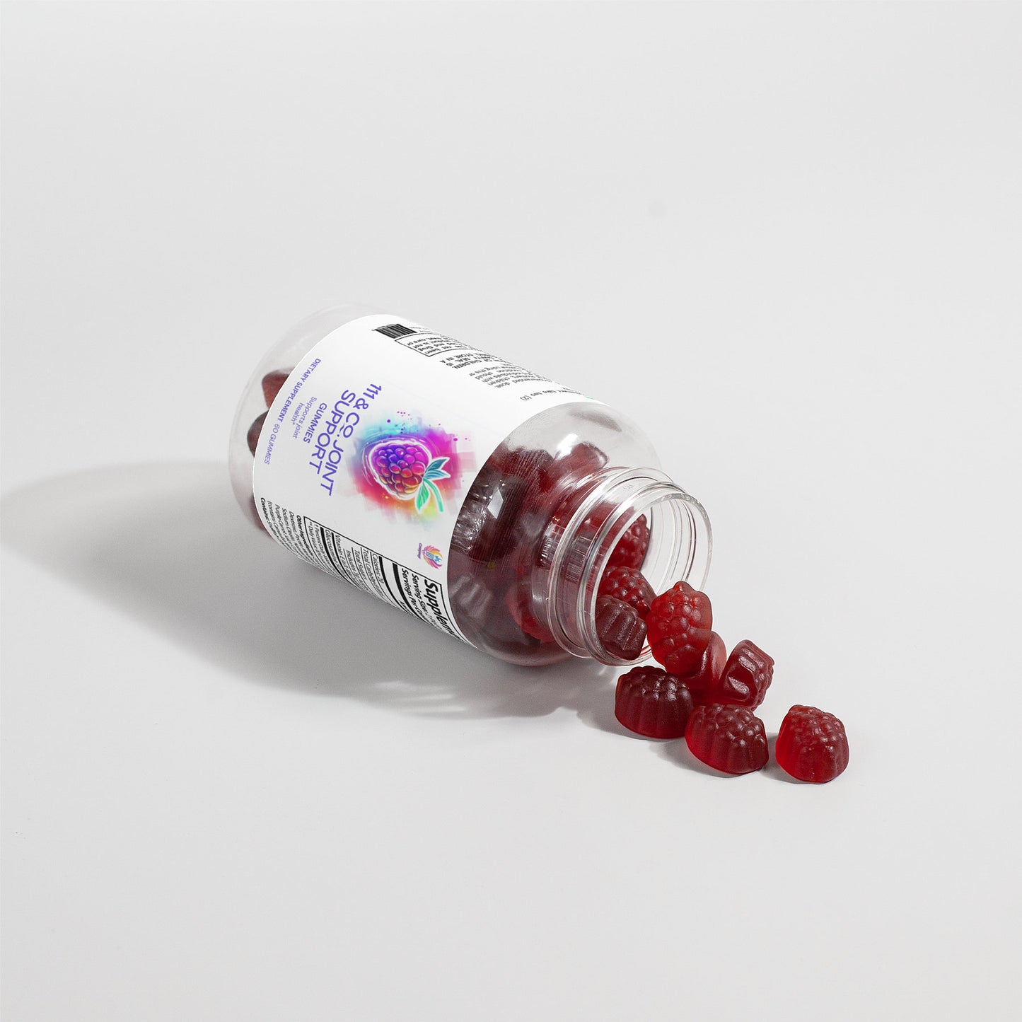 A tipped-over clear plastic bottle with a white label reveals 111 & COMPANY JOINT SUPPORT GUMMIES by 111 & Company. These red, raspberry-shaped gummies are infused with raspberry-flavored biotin for joint health, highlighted against a white background accentuating their vibrant color.