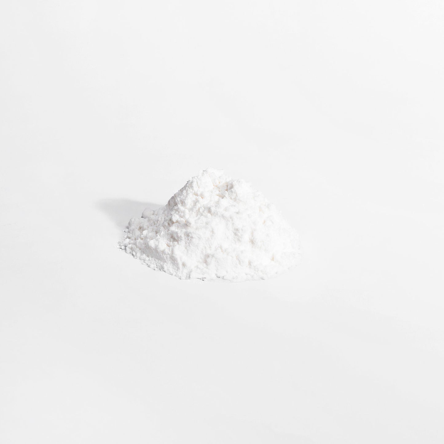 A small, slightly irregular mound of 111 & COMPANY L-GLUTAMINE POWDER from 111 & Company sits on a plain gray background. The fine white powder, celebrated for supporting the immune system, appears soft and fluffy with subtle shadows suggesting light from the left.