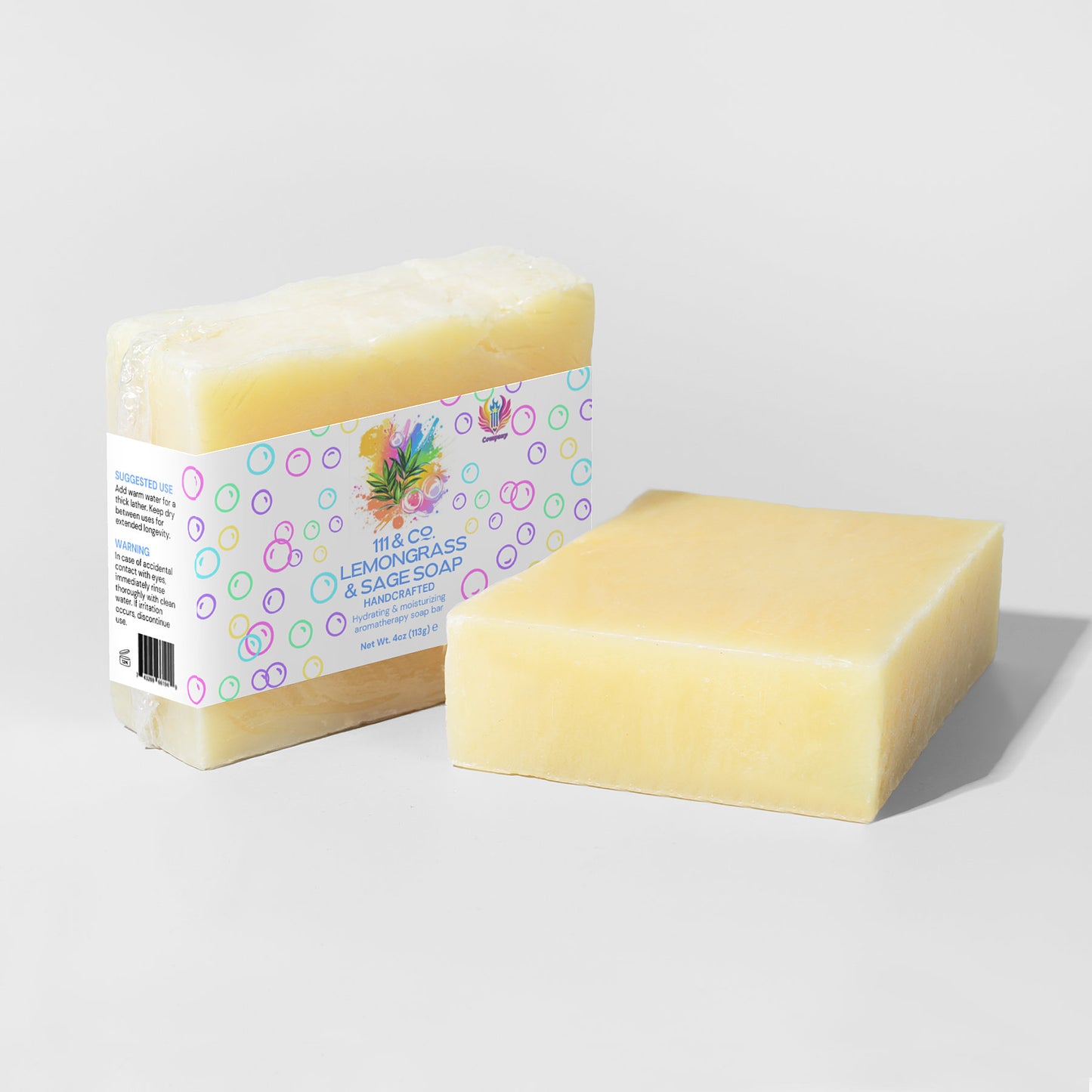 Two yellow soap bars, ideal for sensitive skin, sit against a gray background. One is wrapped in transparent plastic with a colorful label reading 111 & COMPANY LEMONGRASS & SAGE SOAP, by 111 & Company. The other bar is unwrapped, showcasing its smooth, pale yellow surface enriched with organic oils.