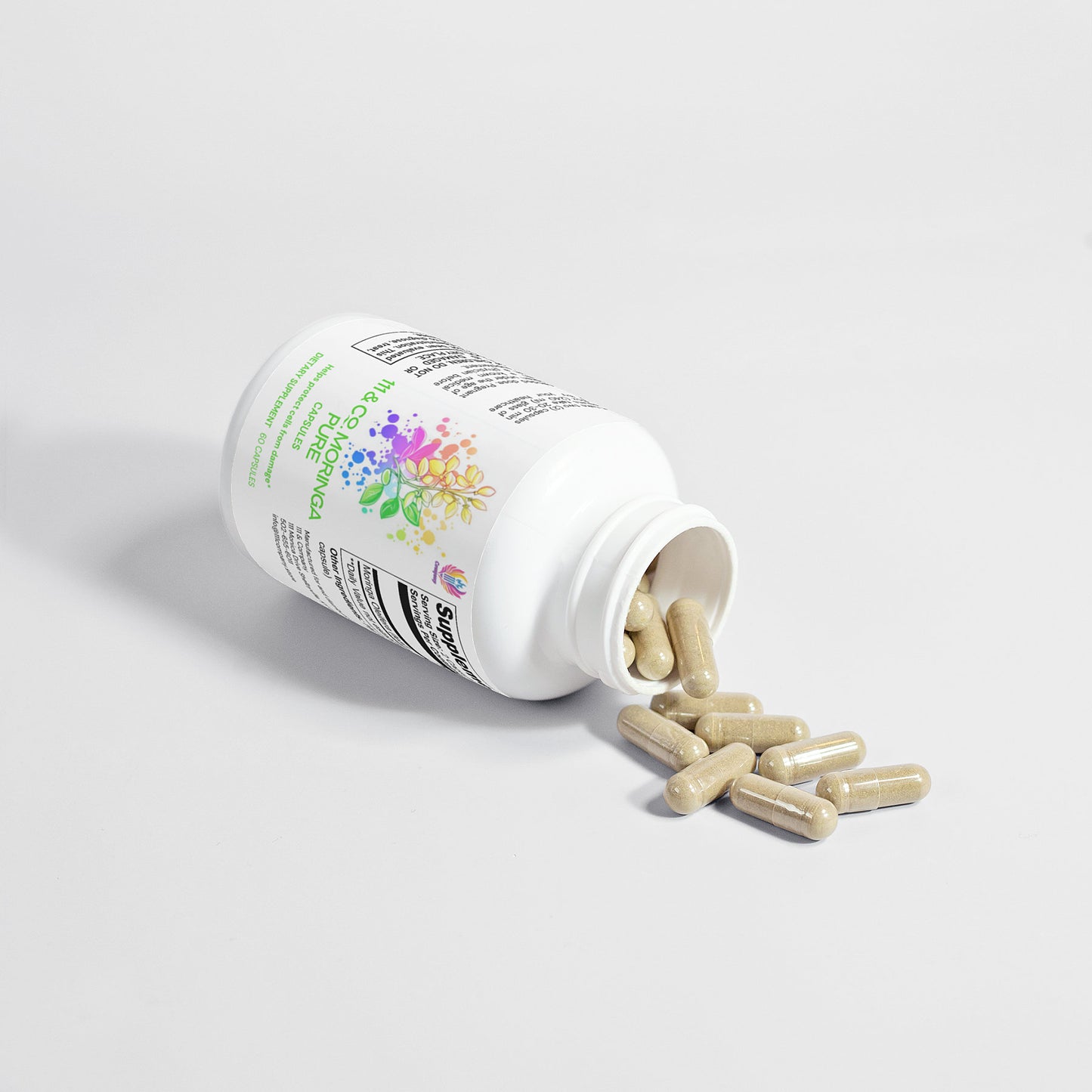 A white bottle labeled 111 & COMPANY MORINGA PURE CAPSULES lies on its side with the cap open, spilling several beige capsules onto a smooth, white surface. The label features colorful graphics and details about the nutrient-rich, vegan-friendly supplement by 111 & Company.