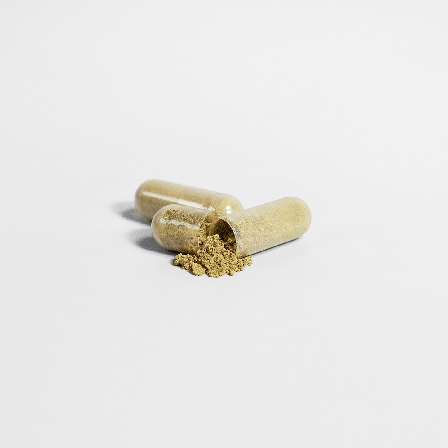 On a white surface lie two transparent capsules of 111 & COMPANY MORINGA PURE CAPSULES. One open capsule spills nutrient-rich beige powder, centered with a minimalist background that emphasizes texture and color, enhancing their vegan-friendly appeal.