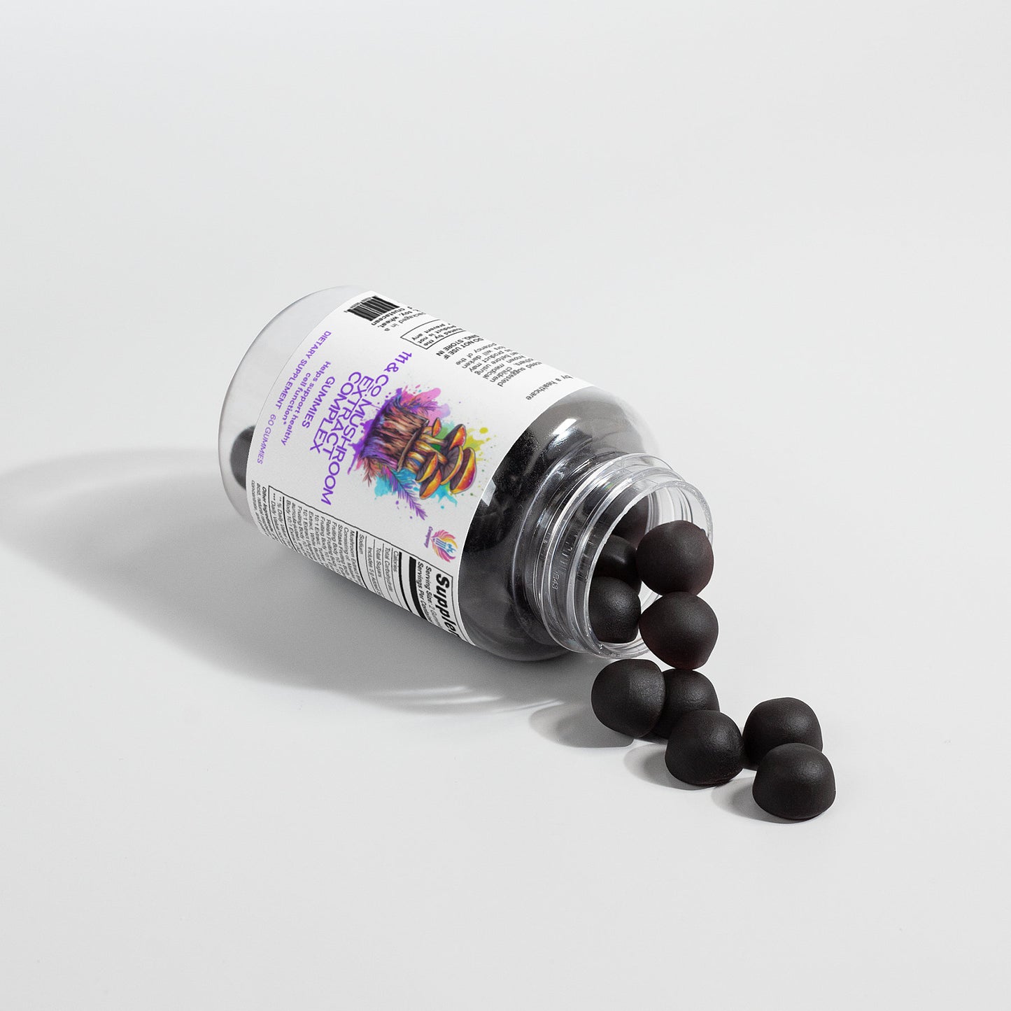 A transparent bottle labeled with 111 & COMPANY MUSHROOM COMPLEX GUMMIES rests on its side, scattering round, black gummies over a white surface. The label displays vibrant graphics and text, while shadows from the bottle and gummies enhance the simple, clean setup.