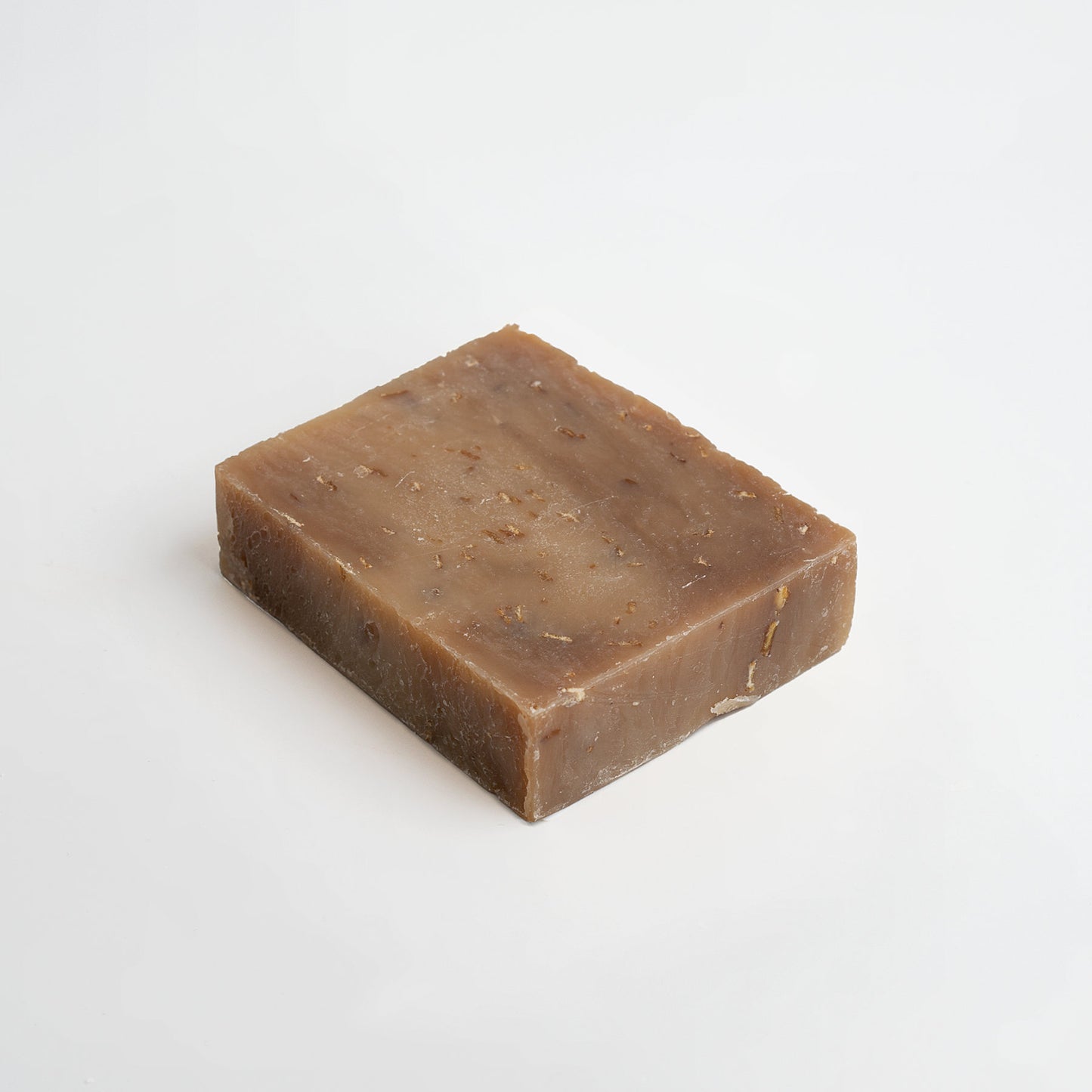 A bar of 111 & COMPANY OAT MILK HONEY SOAP in natural brown sits on a white background. Its textured surface with darker specks suggests a nourishing formula perfect for sensitive skin, while slightly rough edges add rustic charm.