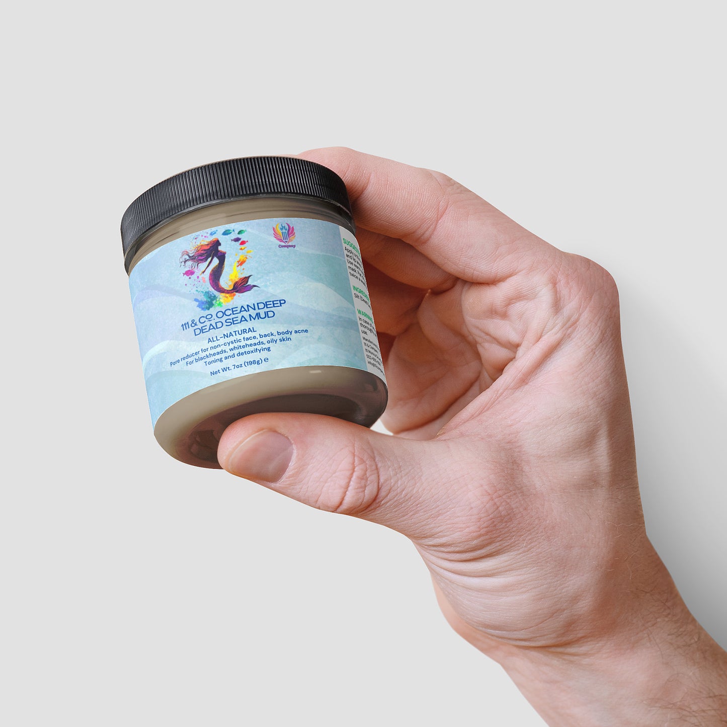 A hand holds a jar labeled 111 & Co. Ocean Deep Dead Sea Mud by 111 & Company, featuring a colorful label with water and mud illustrations highlighting its mineral-rich formula. This natural skincare product weighs 8oz, 226g, against a plain white background.