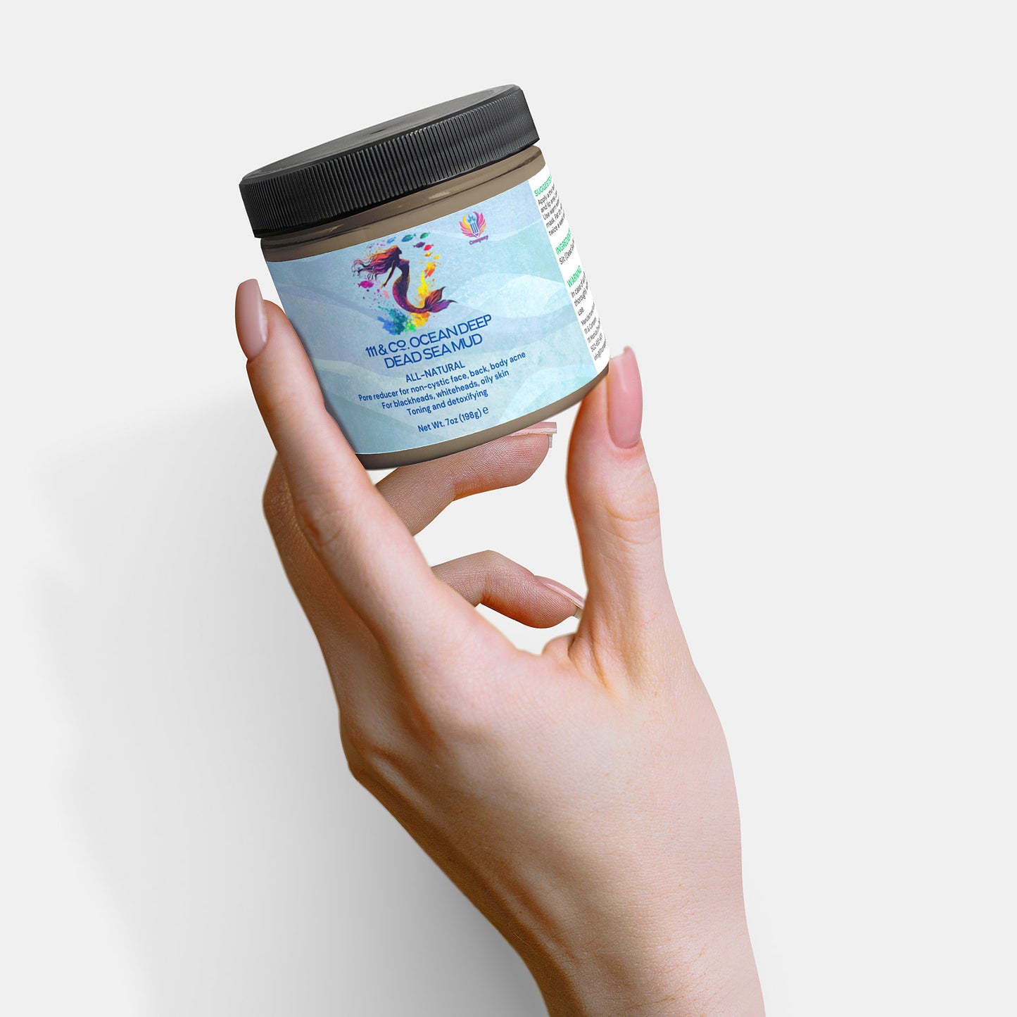 A hand with manicured nails holds a small jar featuring a black lid. The label displays vibrant artwork and text, emphasizing 99% CO2 Ocean Deep and Red Seaweed Algae Mask, highlighting its natural skincare appeal. Set against a plain white background, it draws attention to 111 & Company OCEAN DEEP DEAD SEA MUD.