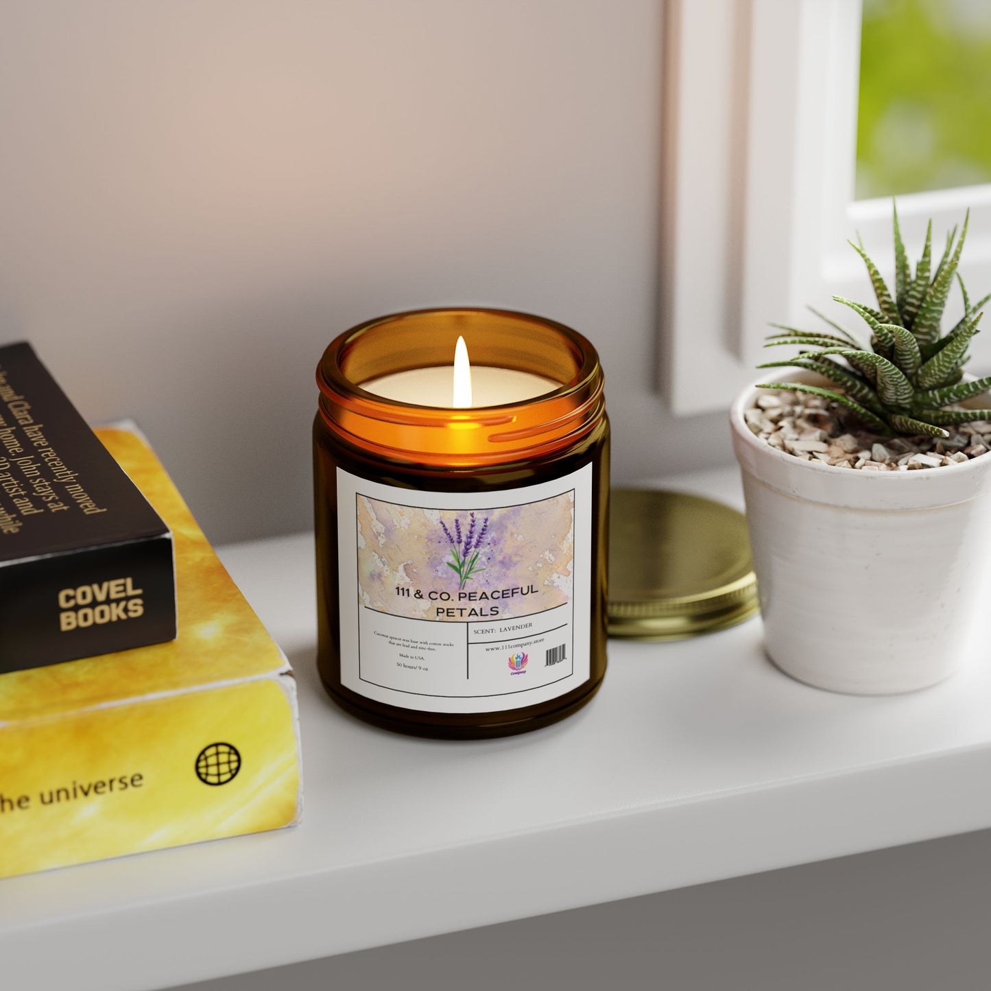 A lit 111 & COMPANY Peaceful Petals Lavender Scented Candle in an amber jar sits on a white shelf, exuding relaxation. Nearby, a small potted succulent and books like the universe enjoy the soft natural light, creating an eco-friendly ambiance.