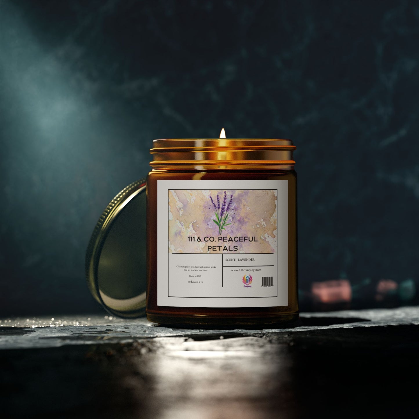 A lit 111 & Company Peaceful Petals candle in an amber jar emits calming relaxation, marked as White Lavender with an eco-friendly barcode. The lid sits nearby on a stone surface, amid a dark, blurry backdrop with part of a pink object visible.