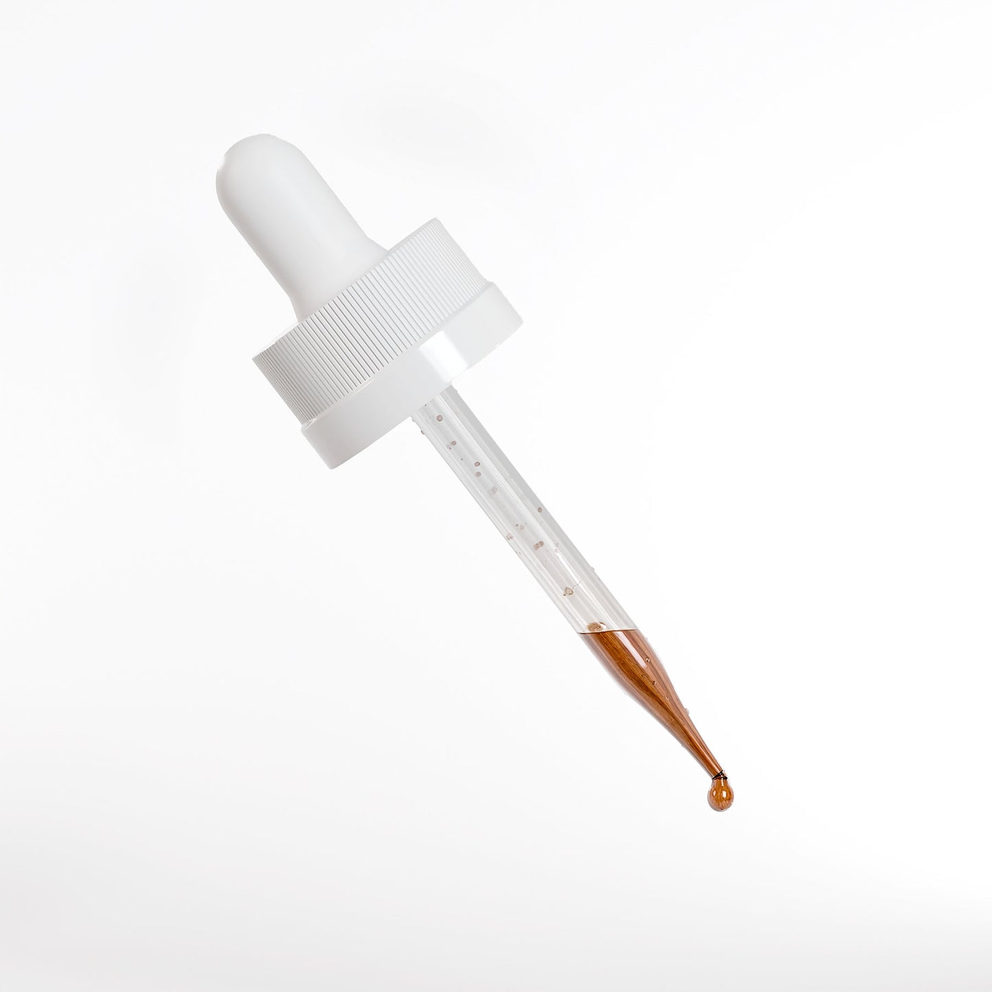 A glass dropper with a white rubber top holds the metallic copper-toned 111 & COMPANY PEPTIDE HAIR GROWTH SERUM from 111 & Company. A droplet forms at the tip against a clean white background, with the dropper angled diagonally.