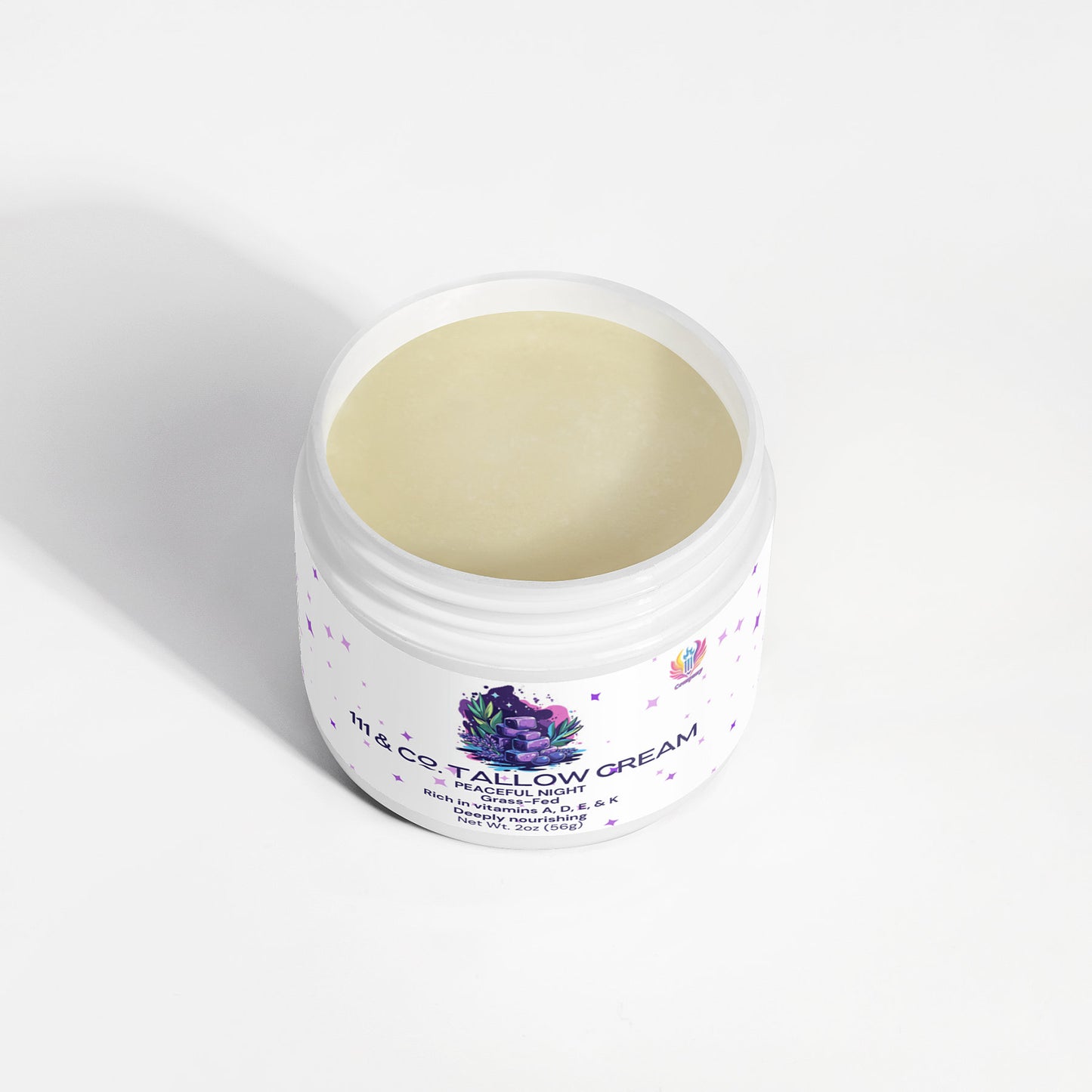 An open jar of 111 & Company Tallow Cream Peaceful Night by 111 & Company sits on a white surface, with colorful abstract artwork adorning the label. This pale yellow, smooth cream is designed for face, body, hands, and feet and is high in vitamin C and rich in fatty acids.