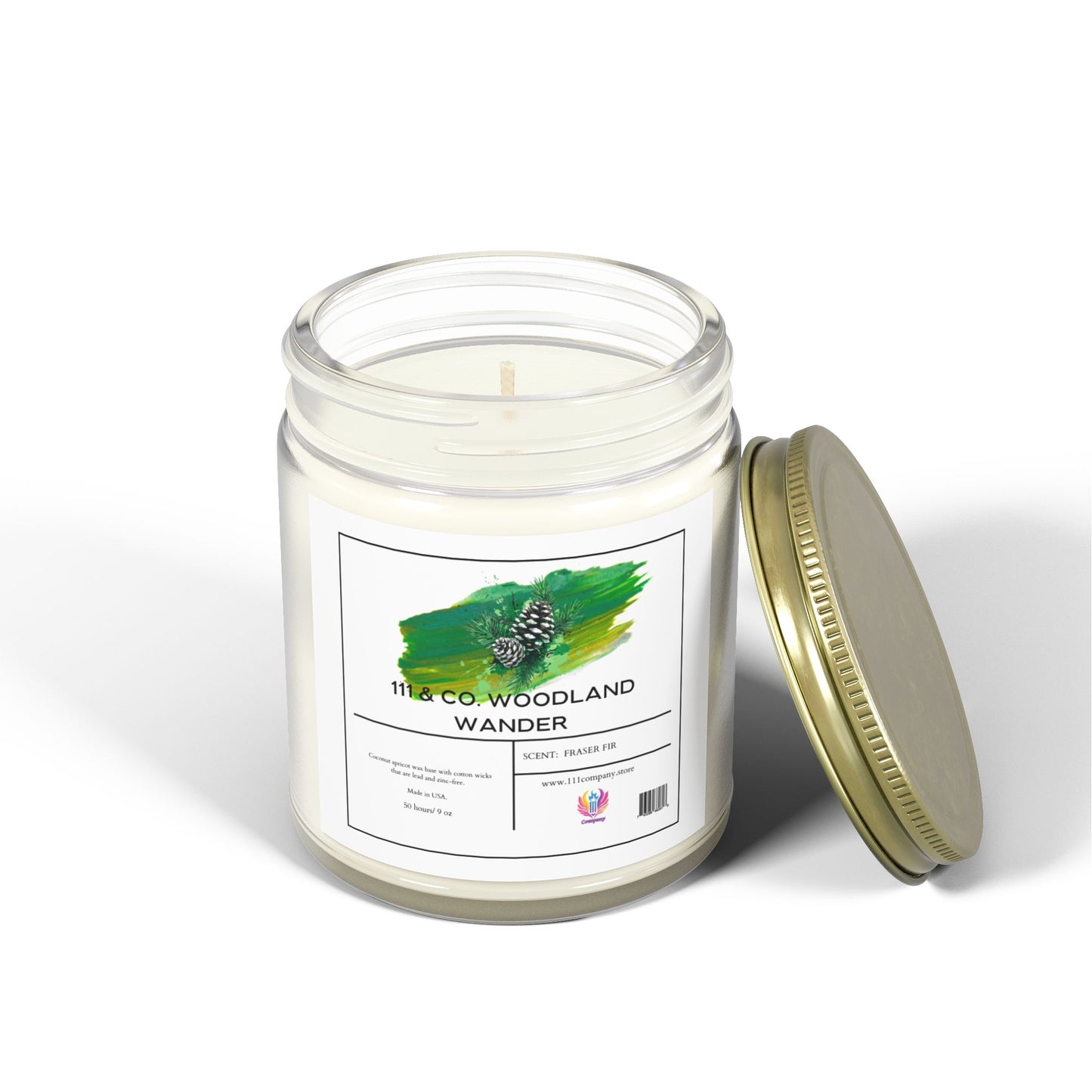 The 111 & Company Woodland Wander Fraser Fir Scented Candle by 111 & Company features eco-friendly coconut apricot wax in a clear glass jar with a gold lid. It has an unlit wick, burns long, and is decorated with a green brushstroke and pinecone on the label indicating the fresh pine scent.