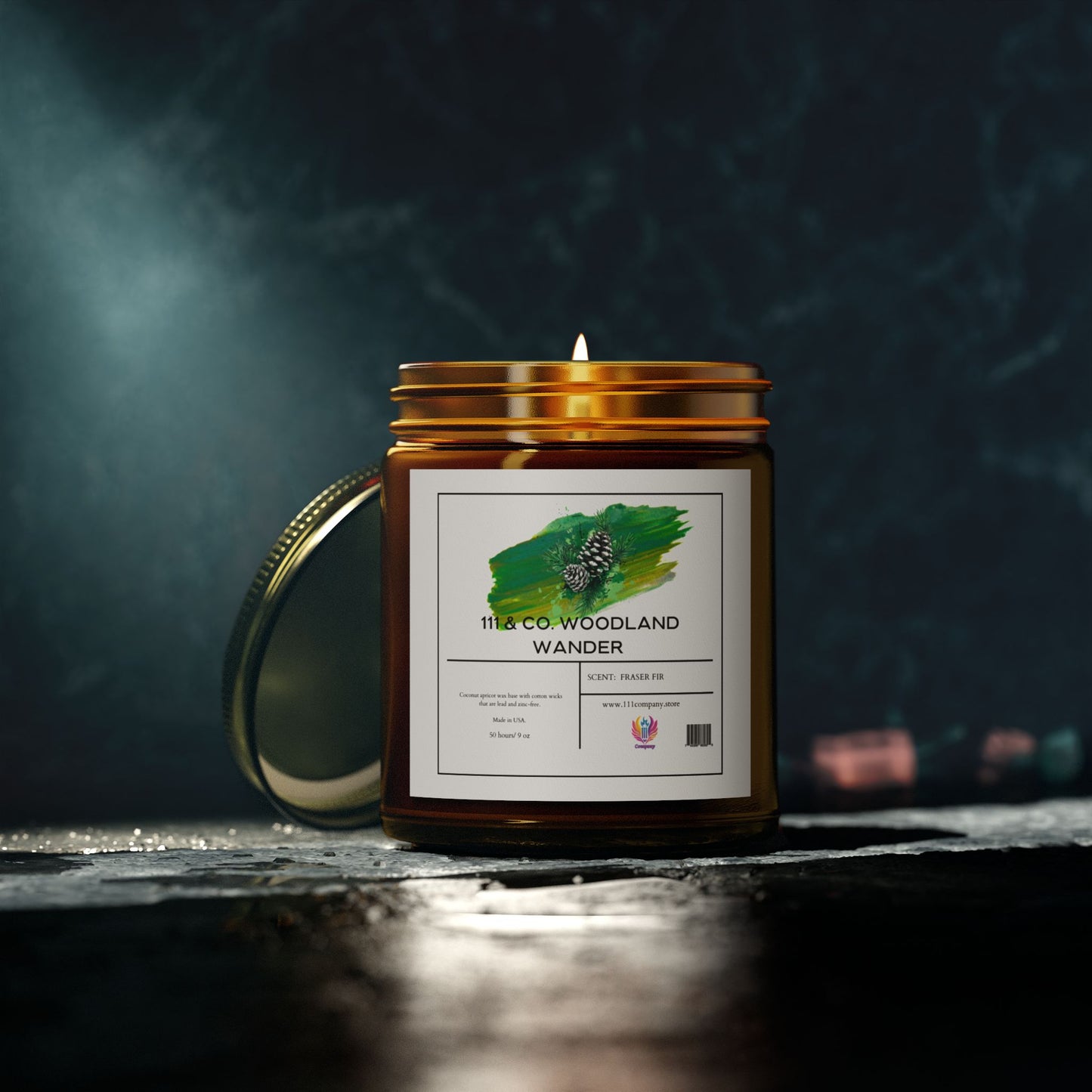 An amber jar candle labeled 111 & Company Woodland Wander Fraser Fir made from natural Coconut Apricot Wax rests on a dark surface, its lid slightly ajar. The label features a green brushstroke with a pinecone, softly spotlighted to cast gentle shadows. Brand: 111 & Company.