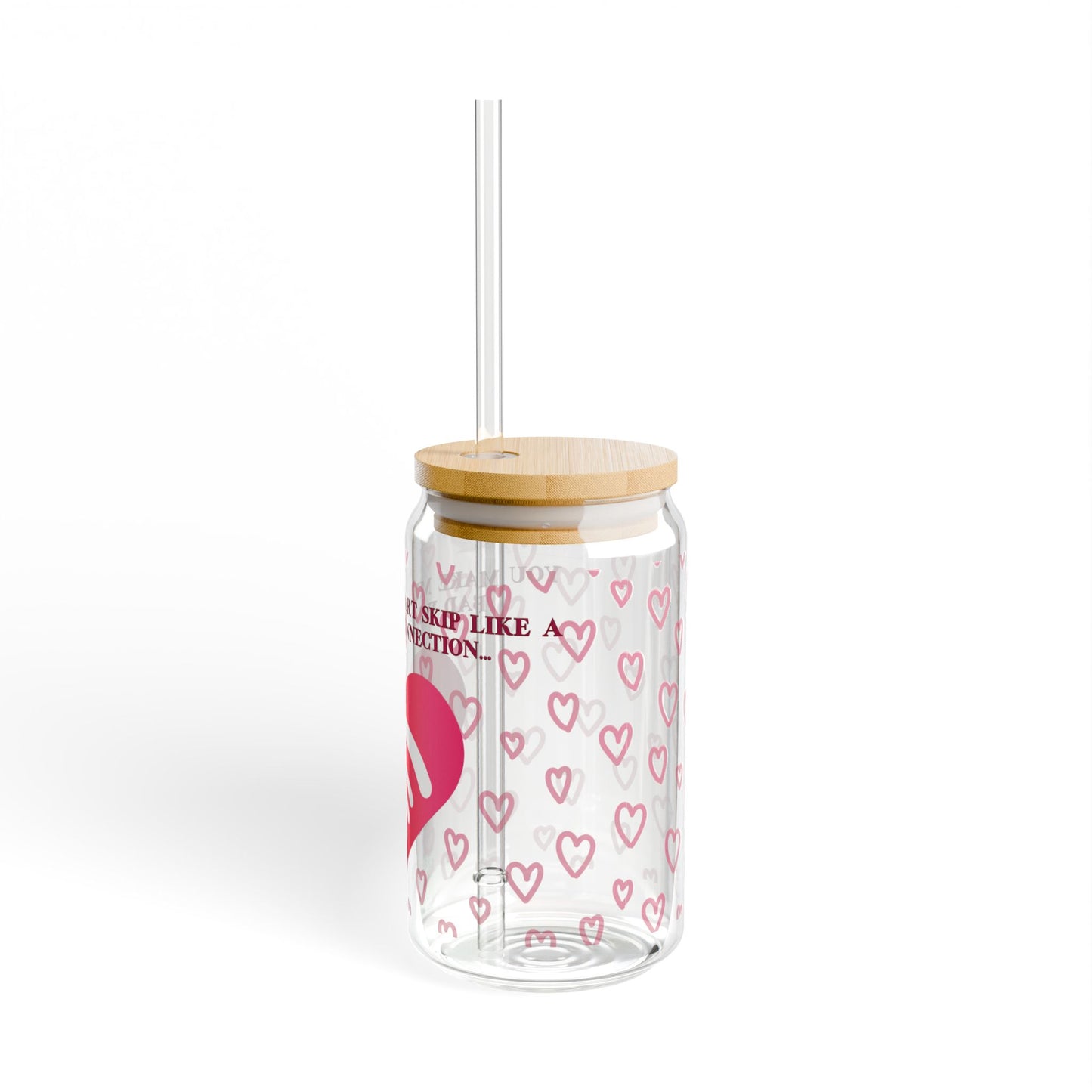 The VALENTINES WIFI SIPPER GLASS by 111 & Company offers a unique drinkware experience with vibrant pink heart patterns on transparent glass. Featuring a wooden lid and clear straw, its playful touch is enhanced by the text Skip Like A Rejection against a plain background.