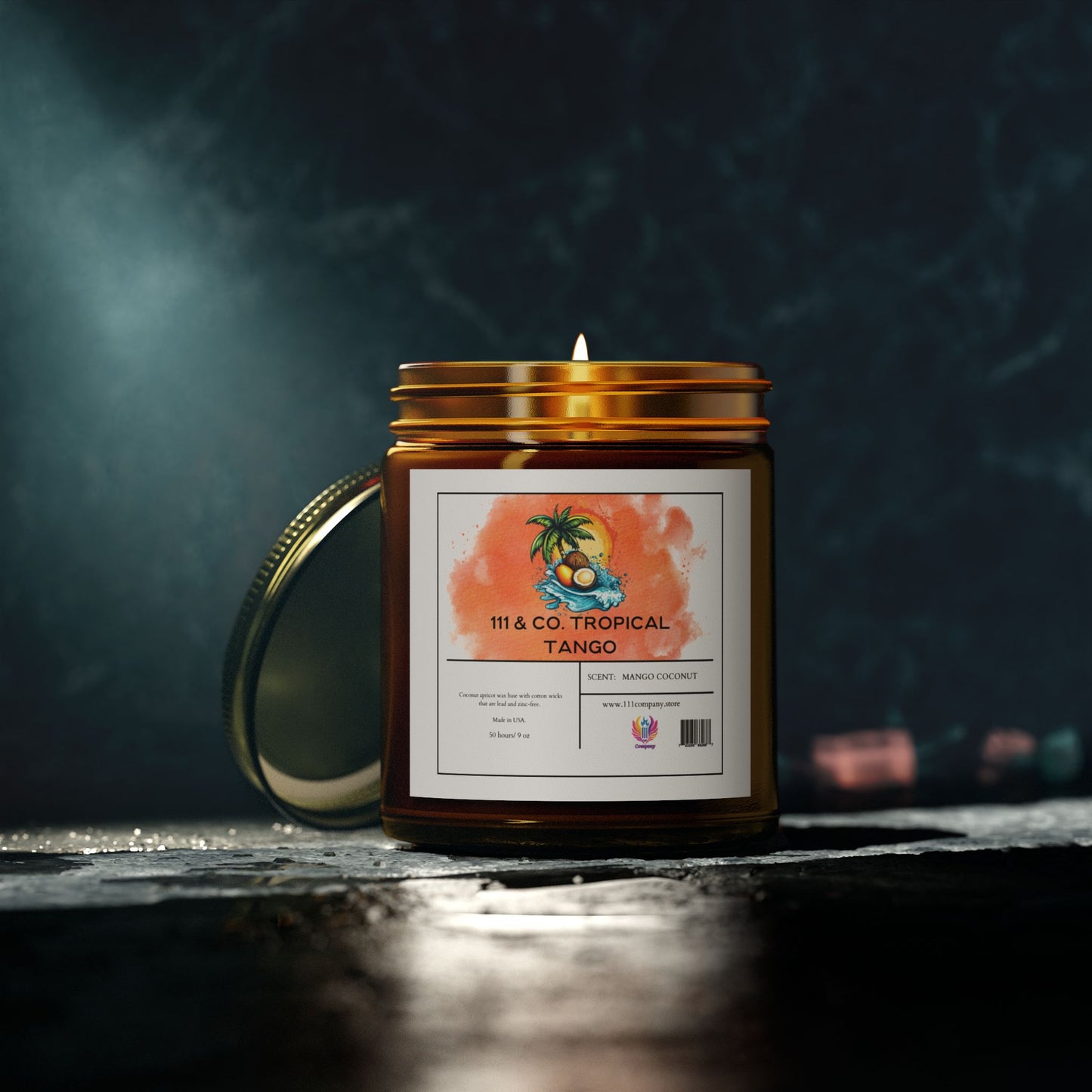 A lit candle in an amber jar labeled Printify 111 & Co. Tropical Tango Coconut Mango Scented Candle rests on a dark surface. The eco-friendly label features a palm tree and orange watercolor design. A tropical fragrance fills the air, with its metal lid placed behind it against a blurred, textured wall.