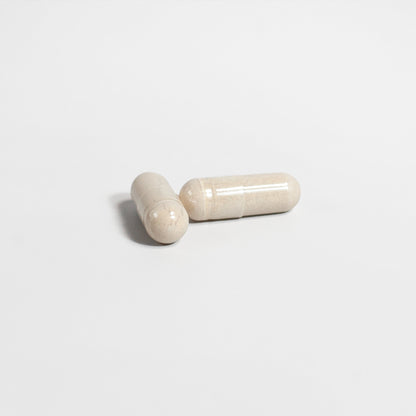 Two beige capsules of 111 & Company ALPHA ENERGY rest on a plain white surface, one horizontal and the other diagonally propped, embodying simplicity while supporting mens health and promoting cardiovascular wellness.