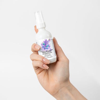 A manicured hand holds a white spray bottle labeled 111 & Co. Anti Aging Moisturizer for Sensitive Skin. The label shows purple flowers and green leaves, suggesting benefits for skin elasticity. The background is plain white.