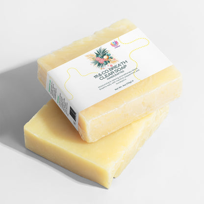 Two pale yellow handmade soaps are stacked on a gray surface. The top bar, labeled 111 & COMPANY BREATHE CLEAR SOAP, showcases floral illustrations and emphasizes its natural benefits for sensitive skin. The bottom bar is plain, highlighting the soaps texture.