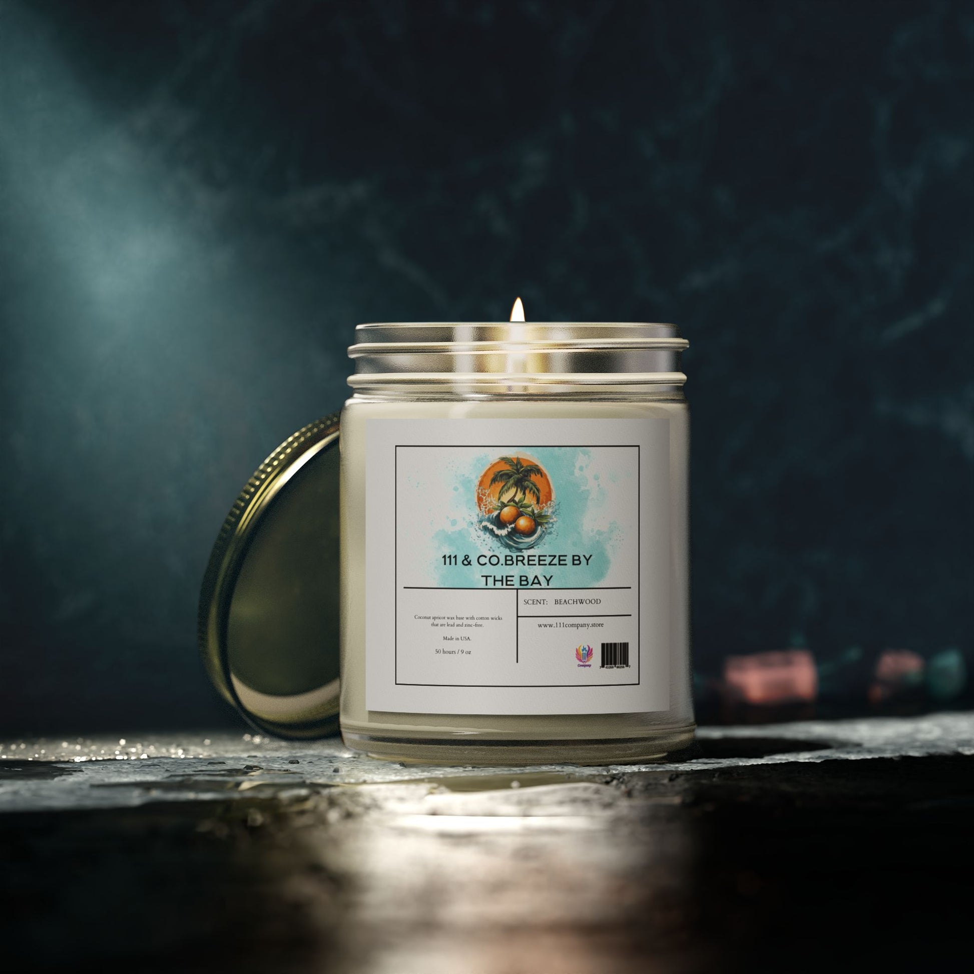 A lit 111 & Company Breeze by the Bay Beachwood scented candle rests on a textured surface, in a clear glass jar with a metallic lid. Made from eco-friendly coconut apricot wax, it exudes a coastal escape essence, set against a dark, blurred background for added coziness.