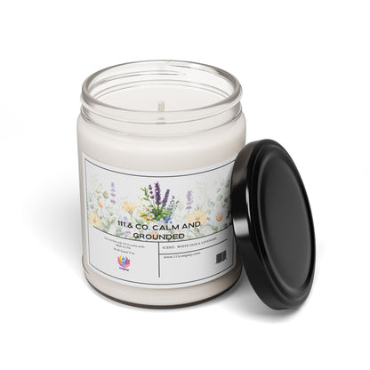 The 111 & COMPANY Calm and Grounded candle by 111 & Company, featuring a lavender and white sage scent, rests in a clear glass jar adorned with floral and greenery illustrations. The black lid accompanies the jar on a pristine surface, inviting relaxation through its soothing aroma.