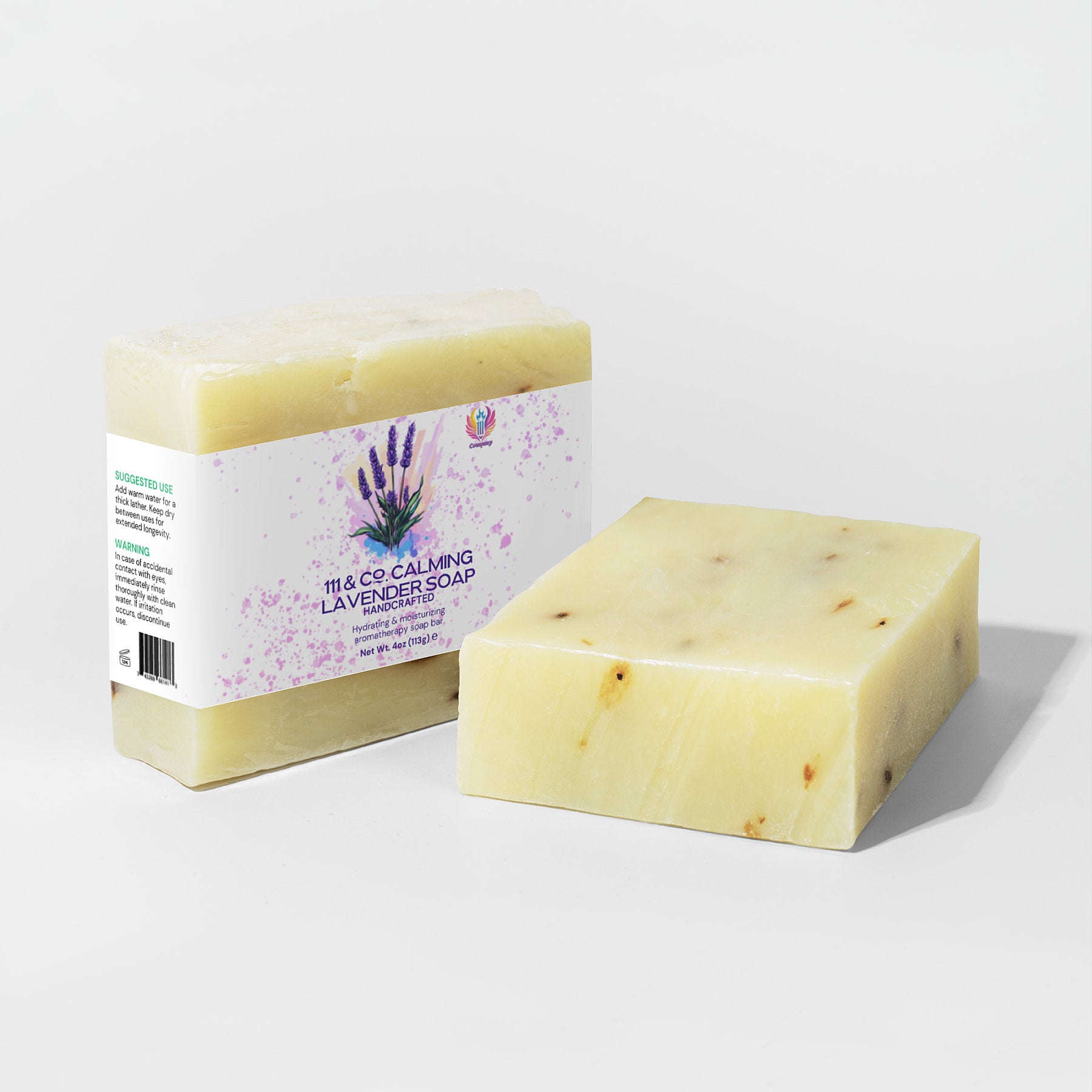 Two bars of soap are displayed. The left one is wrapped with a 111 & Company Calming Lavender Soap label featuring purple lavender illustrations, perfect for sensitive skin. The right one is unpackaged, revealing its creamy color speckled with dark flecks against a white background.
