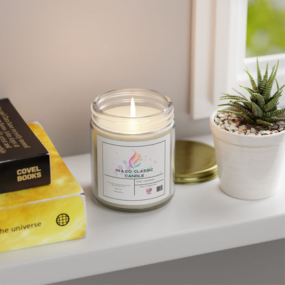 A lit 111 & Company Classic Unscented Candle in a clear jar sits on a white shelf. Made from eco-friendly coconut apricot wax, it emits a calming glow. Nearby, a potted succulent and two yellow books—one titled Covel Books, the other with planet imagery—enhance the decor as daylight filters through the window.