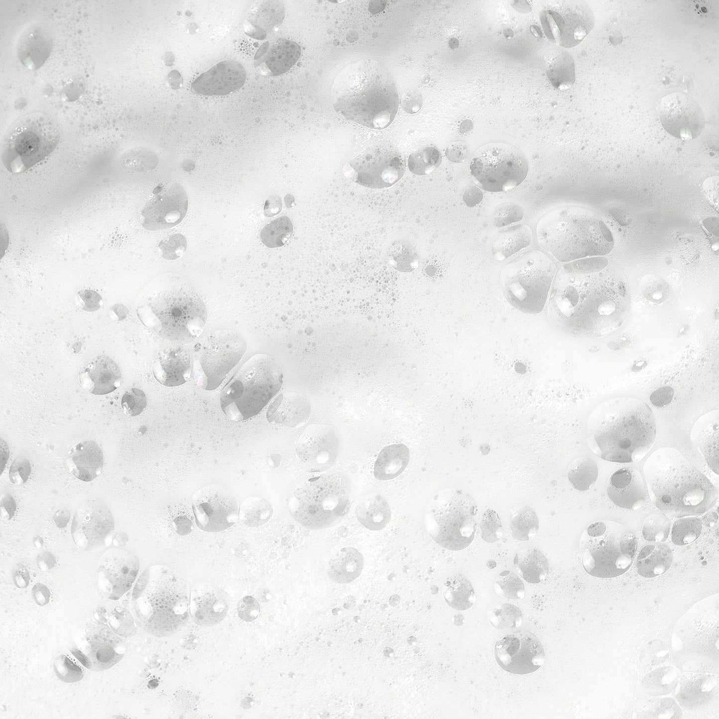 Close-up of white soap bubbles on the surface, reminiscent of 111 & COMPANY DOG WATERLESS SHAMPOO. Bubbles vary in size, some larger and defined, others smaller and diffuse. Light reflection enhances a shiny, wet appearance.
