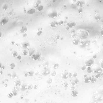 Close-up of white soap bubbles on the surface, reminiscent of 111 & COMPANY DOG WATERLESS SHAMPOO. Bubbles vary in size, some larger and defined, others smaller and diffuse. Light reflection enhances a shiny, wet appearance.
