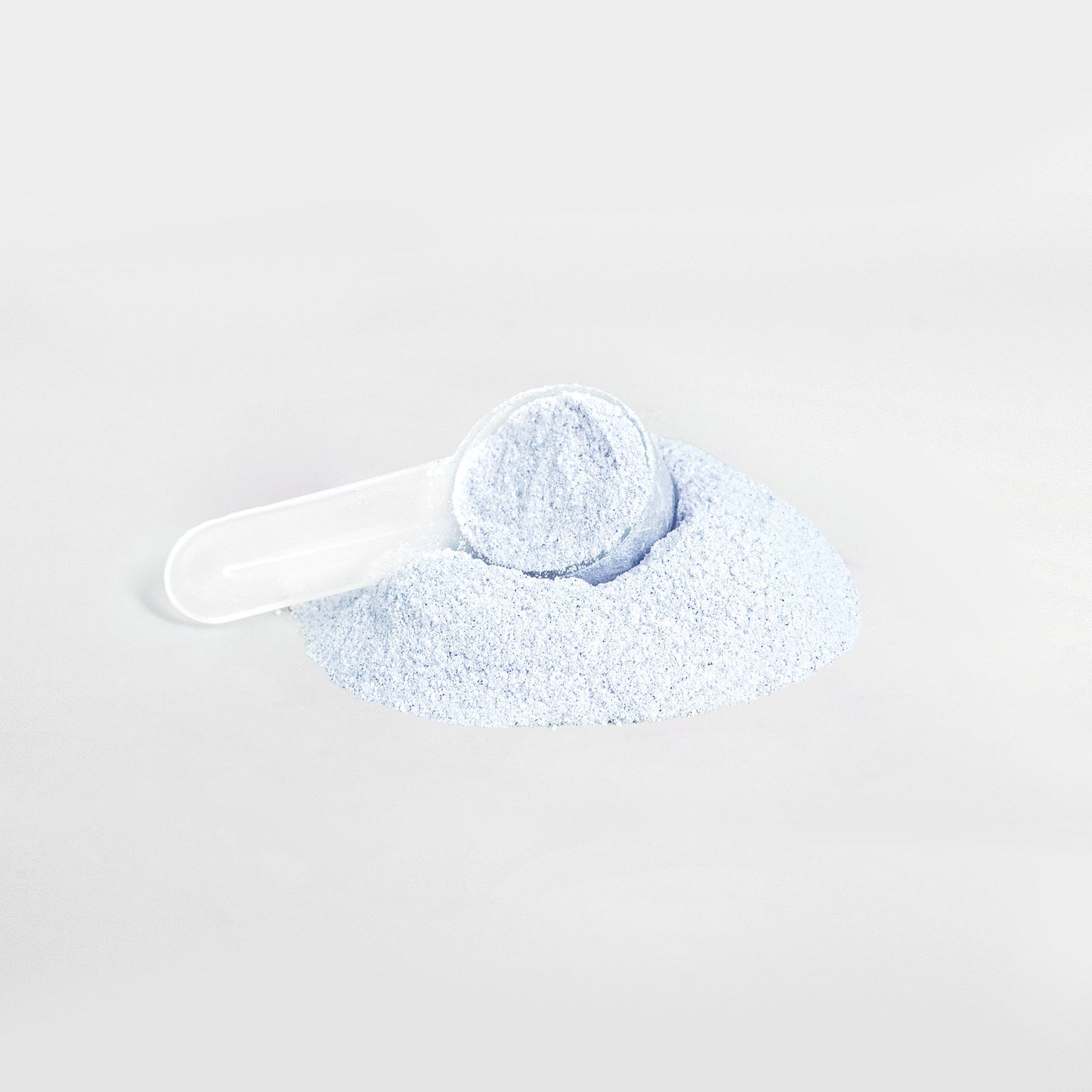 A white scoop partially filled with 111 & COMPANY ENERGY POWDER (COTTON CANDY), a light blue, sugar-free powder from 111 & Company, rests on a pile against a white background. The image features soft, muted colors and is centered to highlight the balanced energy offering.