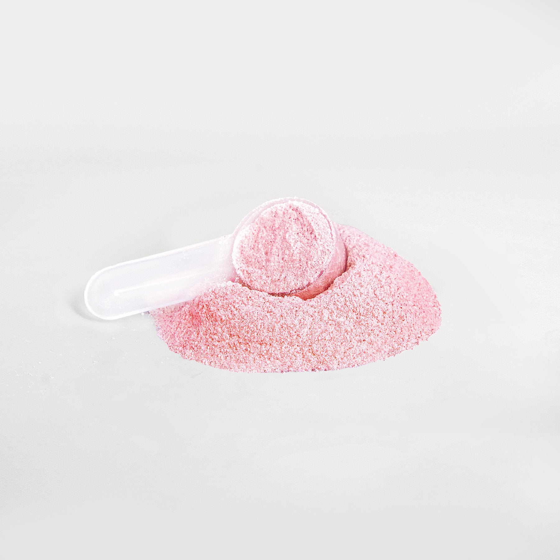 A small, transparent scoop filled with 111 & COMPANY ENERGY POWDER (FRUIT PUNCH) rests on a mound of the same pink powder. The smooth gray background enhances the clean look, reflecting the balanced energy this sugar-free blend from 111 & Company promises.