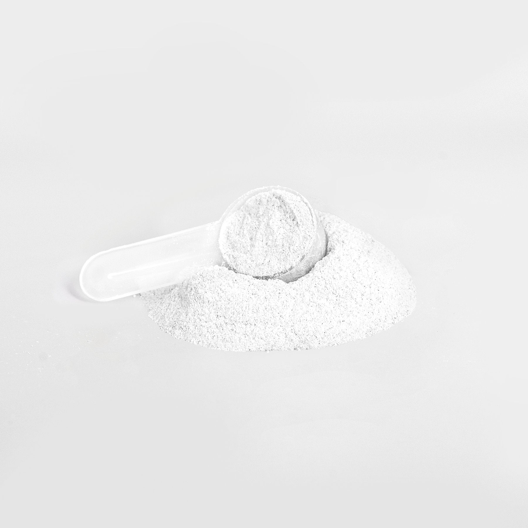 A white plastic scoop rests in a mound of 111 & COMPANY ENERGY POWDER (LYCHEE SPLASH) on a light gray background, filled with sugar-free powder for precise measuring and dispensing.