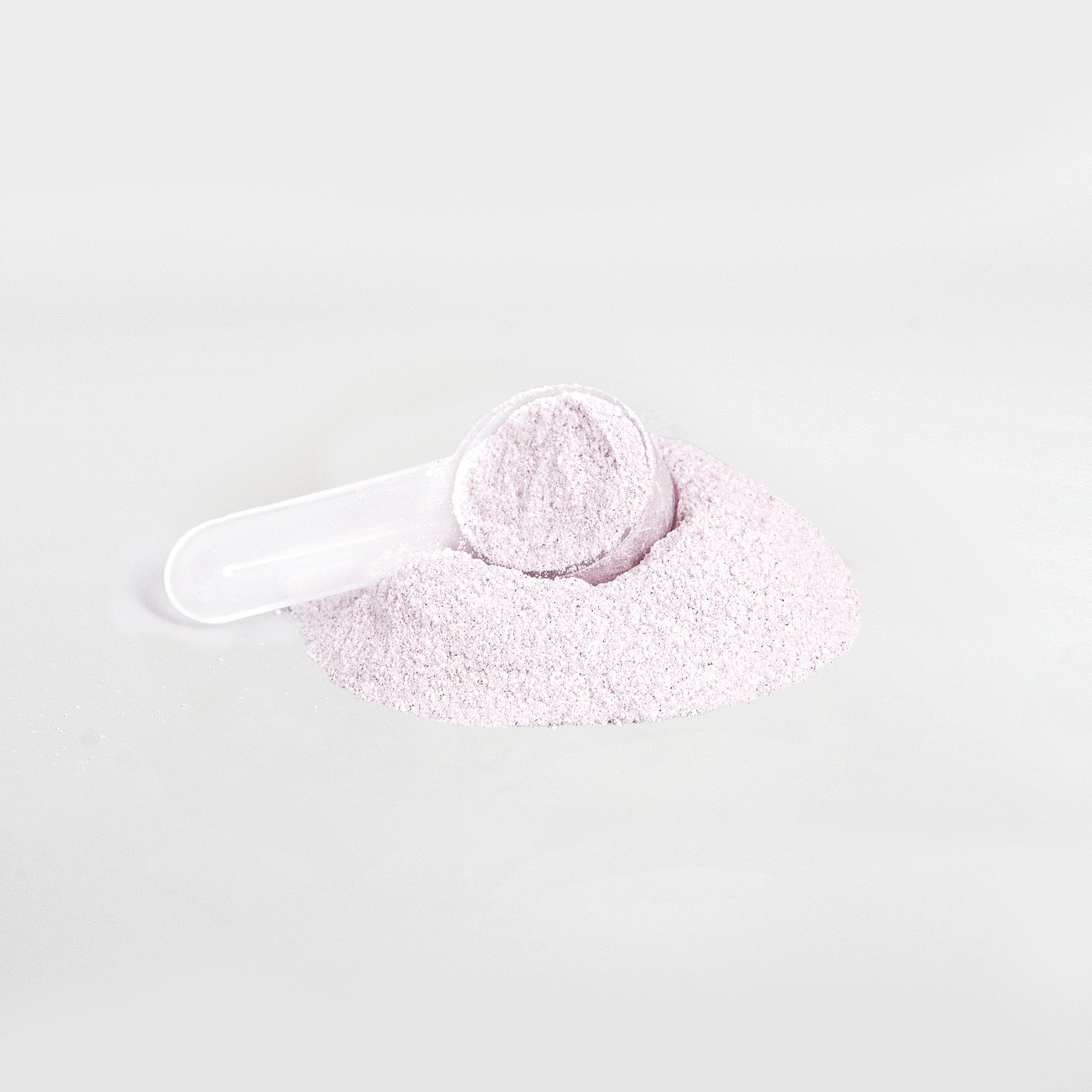 A scoop of 111 & Company Energy Powder (Strawberry Shortcake) sits atop a mound of the same fine, light purple powder on a white background. The transparent scoop is partially filled and lies on its side, showcasing the smooth, sugar-free powder promising balanced energy and delightful taste.