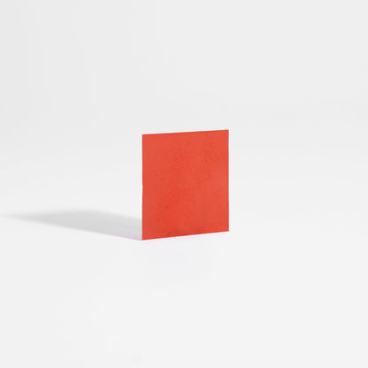 A single red square paper stands upright on a white surface, echoing 111 & Companys Energy Strips in cranberry flavor, which promise mental clarity. Its shadow casts slightly left, suggesting light from the right. The minimal white background enhances its vivid color, mirroring sustained energy simplicity.