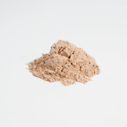 A small heap of light brown fine powder from the 111 & COMPANY FERMENTED MUSHROOM BLEND sits on a plain white surface. Scattered granules hint at its soft texture, enriched with fermented mushrooms by 111 & Company, highlighting its natural hue and potential immune support benefits.