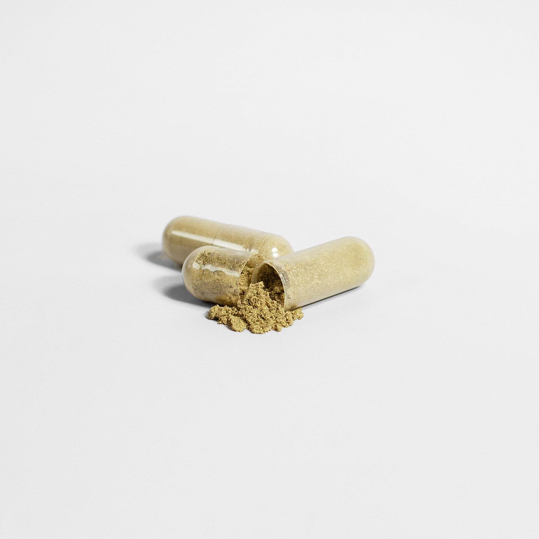 Two capsules of 111 & COMPANY GINKGO BILOBA + GINSENG rest on a white surface; one is open, spilling fine, yellowish herbal powder rich in flavonoids. The minimalistic image features a clean, white background highlighting the capsules and their contents.