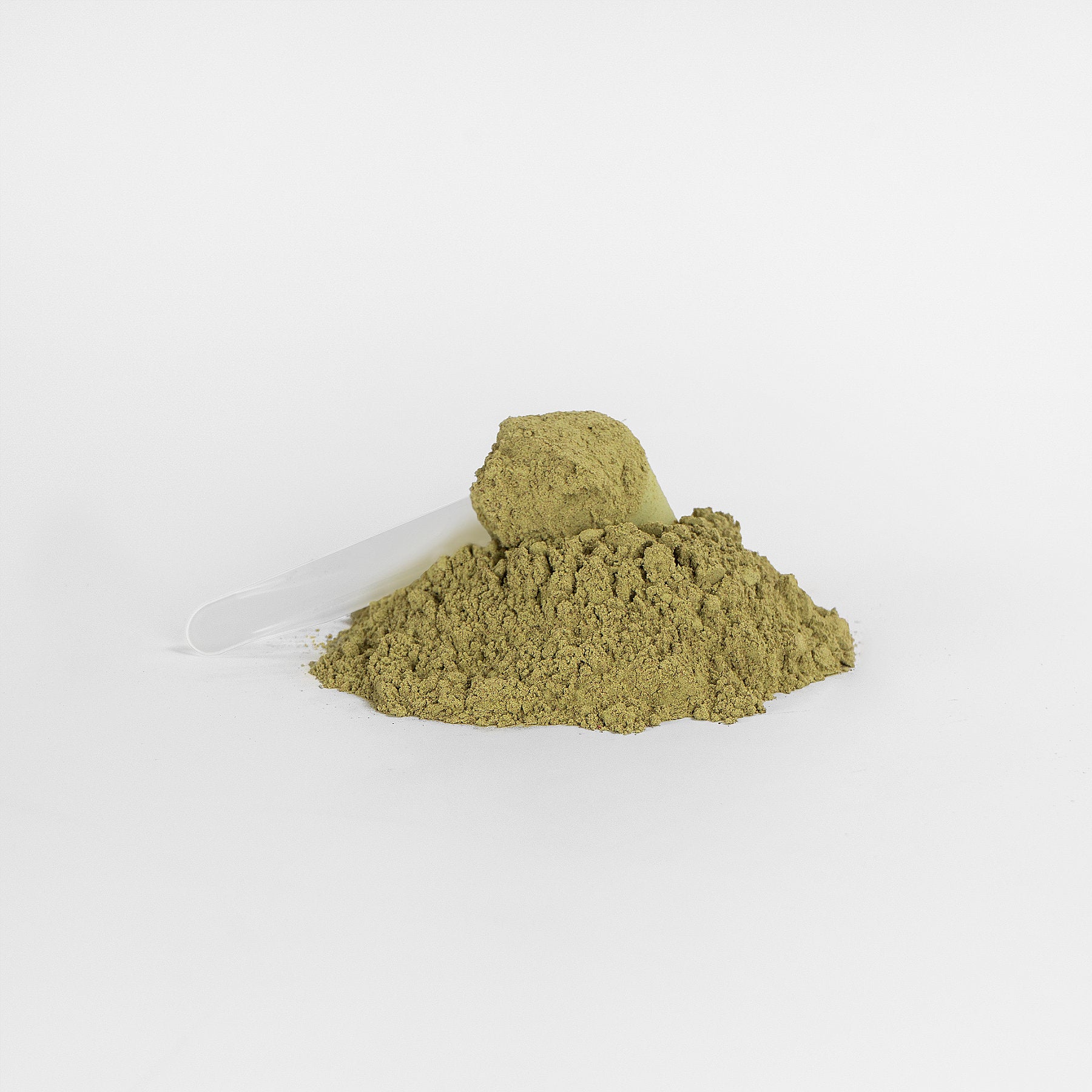 A small scoop with a transparent handle sits atop a mound of fine, light brown powder, 111 & COMPANY GREENS SUPERFOOD by 111 & Company. Resting on a plain white background, this setup highlights the texture and color of this nutrient-rich supplement.