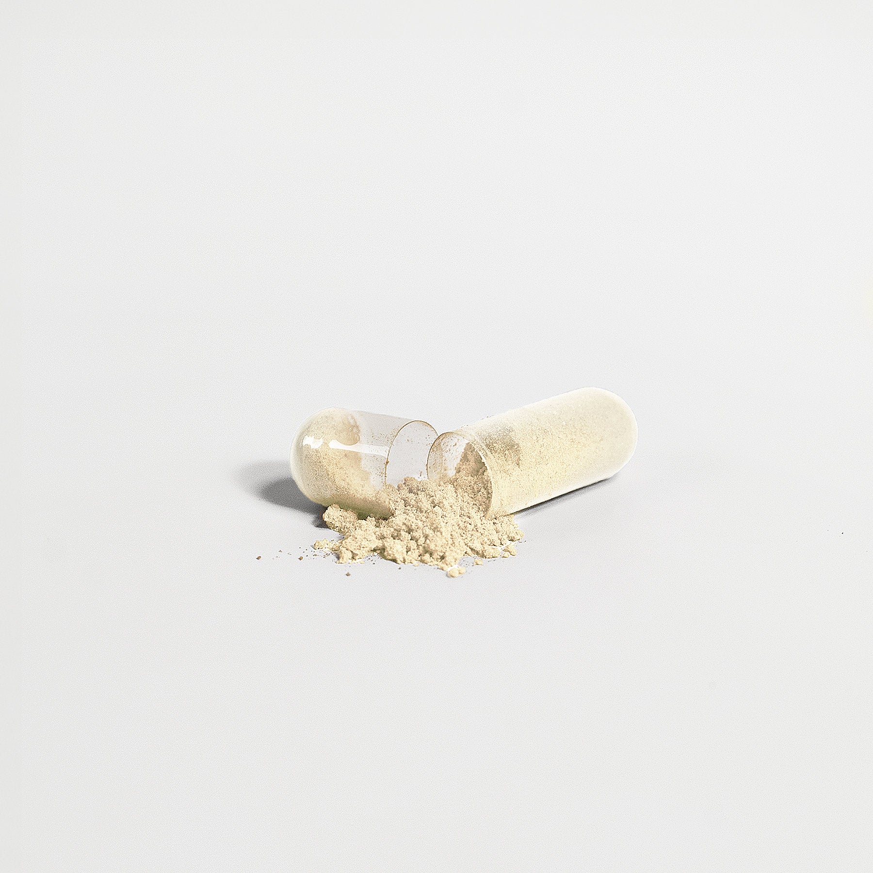 A translucent 111 & COMPANY GUT HEALTH CAPSULE from 111 & Company bursts open on a minimalist, monochrome background, revealing fine beige apple cider vinegar powder. The contrast highlights this natural elixir famed for its gut health benefits.