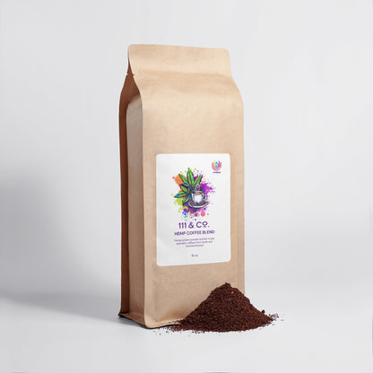 A brown paper bag marked 111 & Co. Hemp Coffee Blend - Medium Roast 16oz by 111 & Company, featuring a vibrant plant illustration, stands on a white surface. Next to it, ground fair trade coffee is spilled, contrasting with the plain setting.