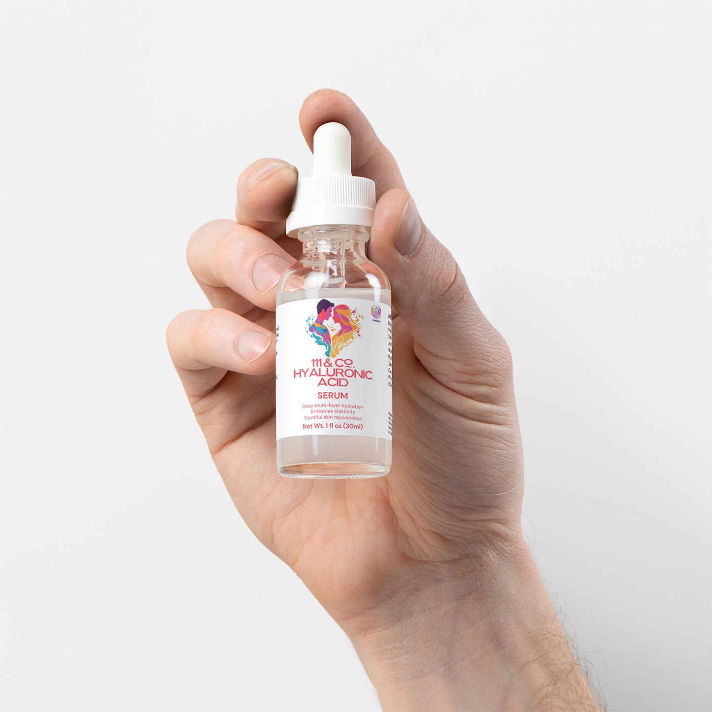 A hand holds a small, clear dropper bottle labeled 111 & COMPANY HYALURONIC ACID SERUM, promising skin rejuvenation. The label features colorful graphics, with a white cap and dropper. The transparent liquid offers hydration, set against a light gray backdrop that highlights its purity.